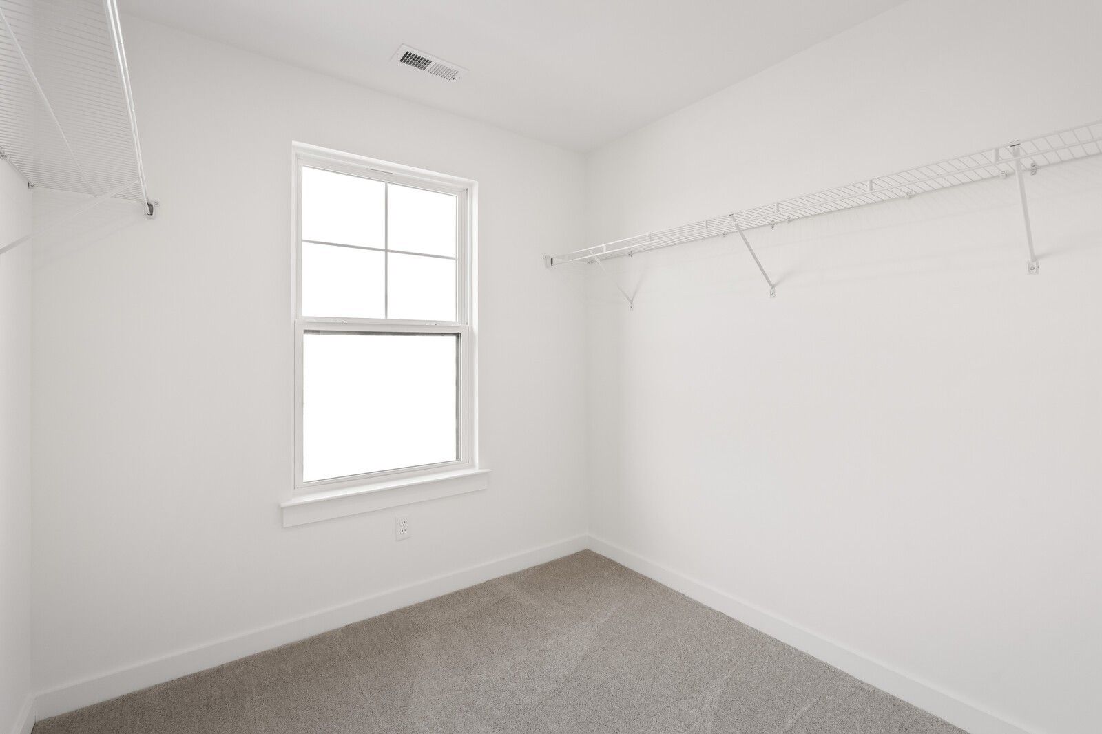 Walk-in closet with white shelving and neutral carpet in The Willow D floor plan at Benders Cove, Mt. Juliet, Tennessee.