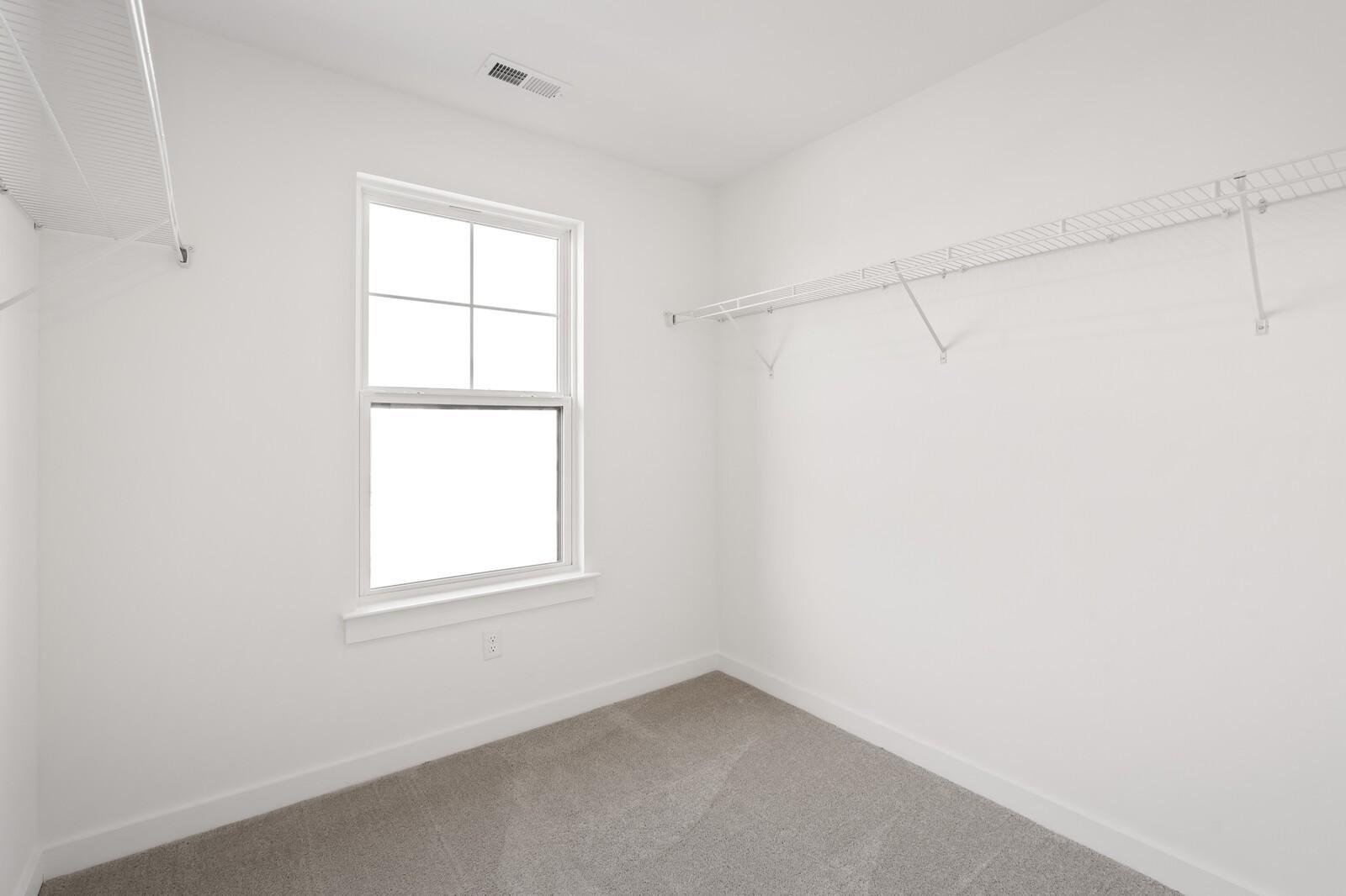 Walk-in closet with white shelving and neutral carpet in The Willow D floor plan at Benders Cove, Mt. Juliet, Tennessee.