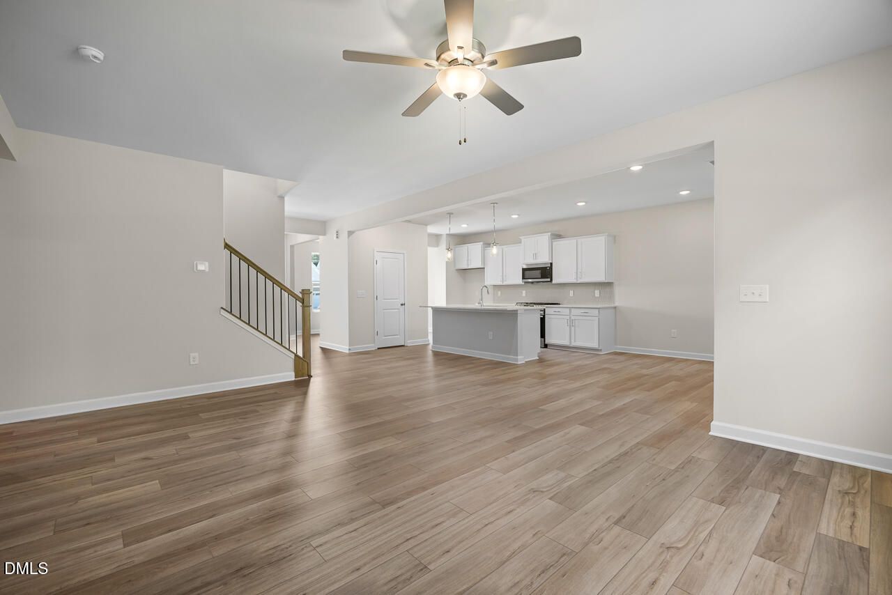 Open-concept living area with wood-look flooring and white kitchen in Davidson Homes The Willow C, Woodland Crossing, Zebulon NC