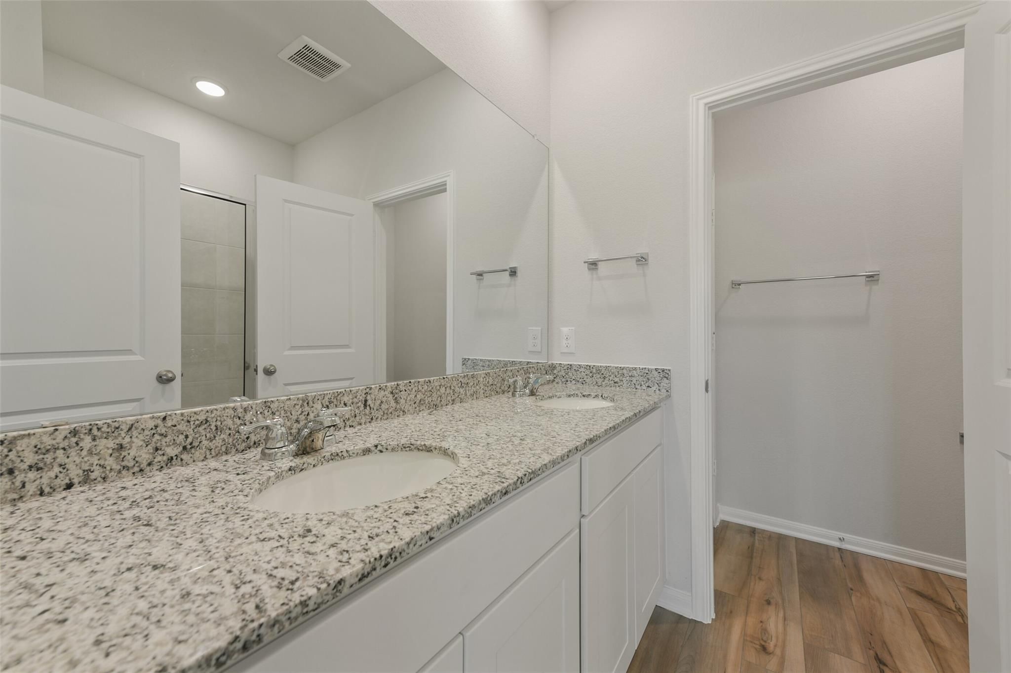 Elegant master bathroom with double granite vanity, mirrors, and walk-in closet access in Davidson Homes The Sabine F, Dayton, Texas