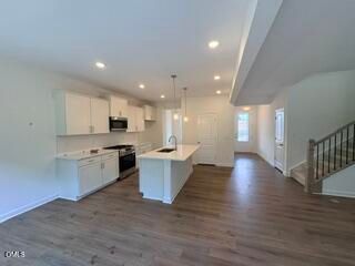 Open-concept kitchen with white cabinets and island in The Willow B floor plan at Woodland Crossing, Zebulon, NC.