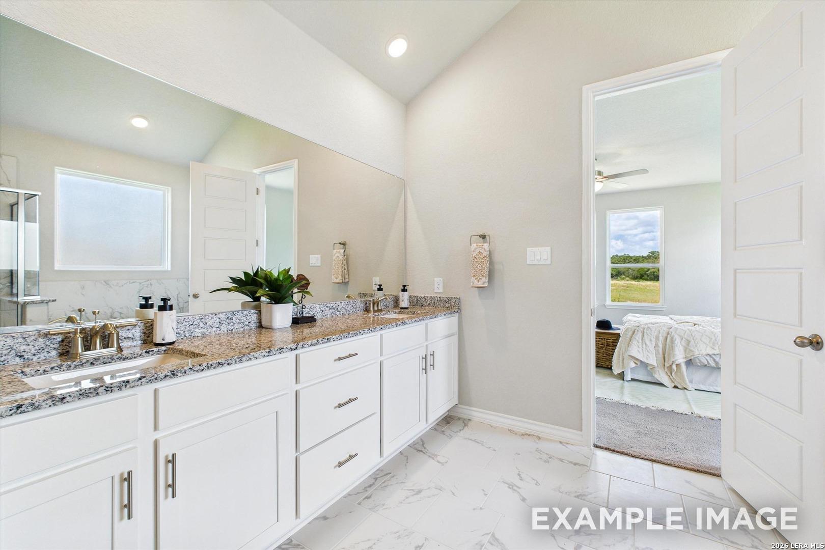 Spacious primary bathroom with dual vanity, granite countertops, and marble-style tile in The Foster F at Potranco Oaks.
