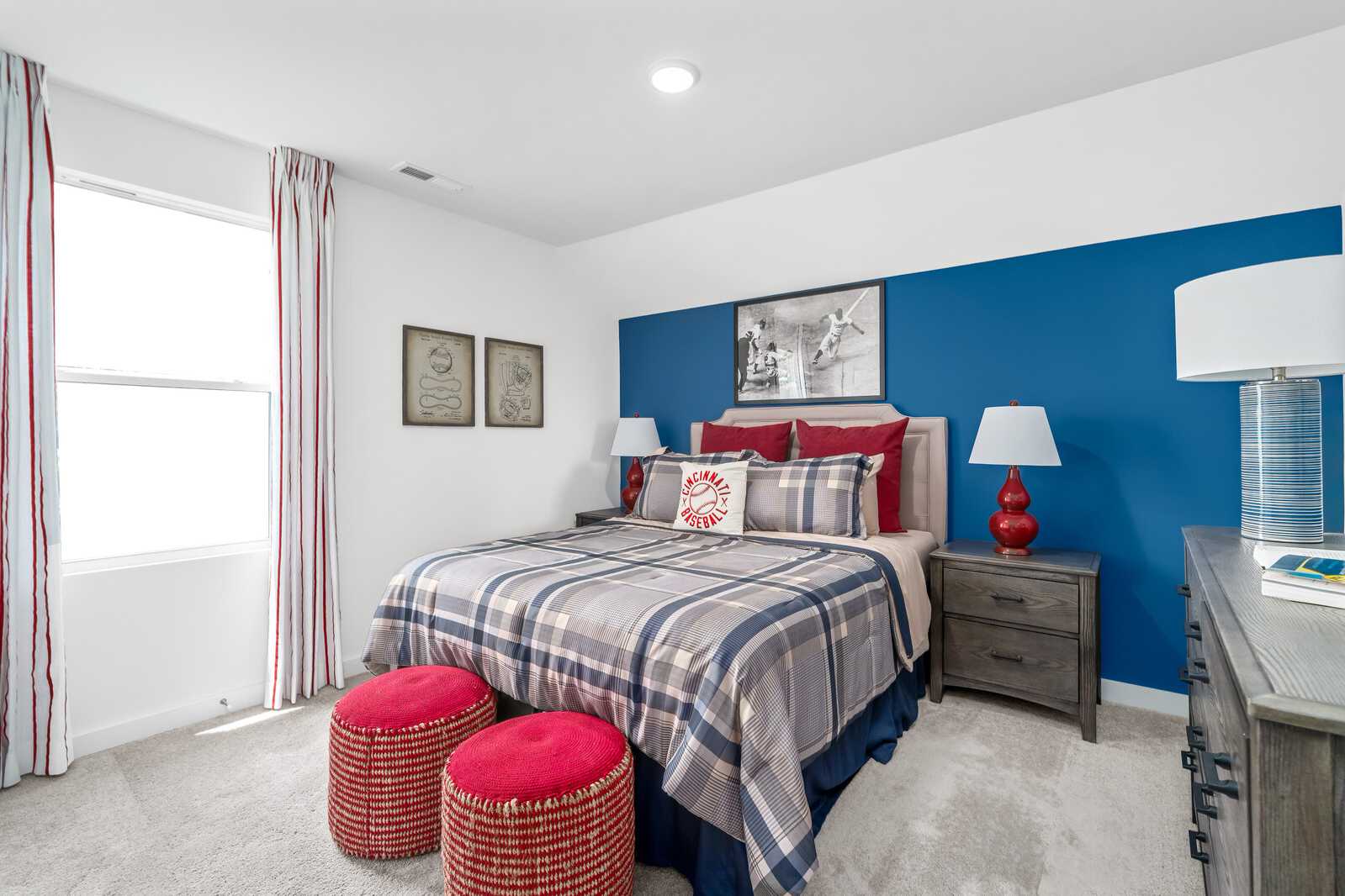 Cozy bedroom at Calista Farms in White House TN featuring blue accent wall, plaid bedding, red pillows and ottomans