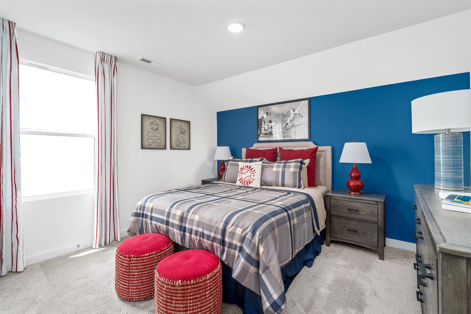 Cozy bedroom at Calista Farms in White House TN featuring blue accent wall, plaid bedding, red pillows and ottomans