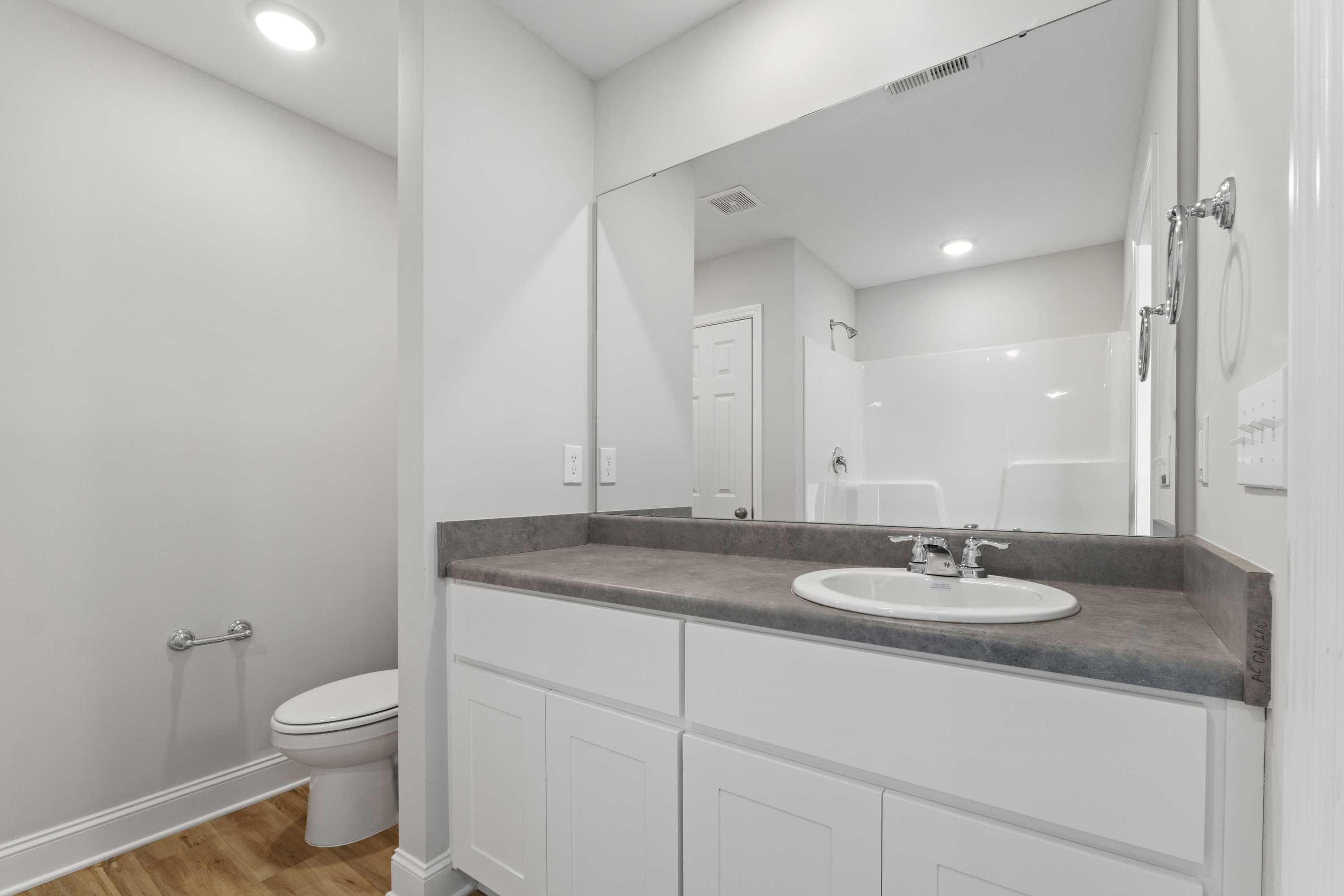 Spacious white bathroom in Chapel Hill Athens AL with double vanity, large mirror, walk-in shower, and recessed lighting