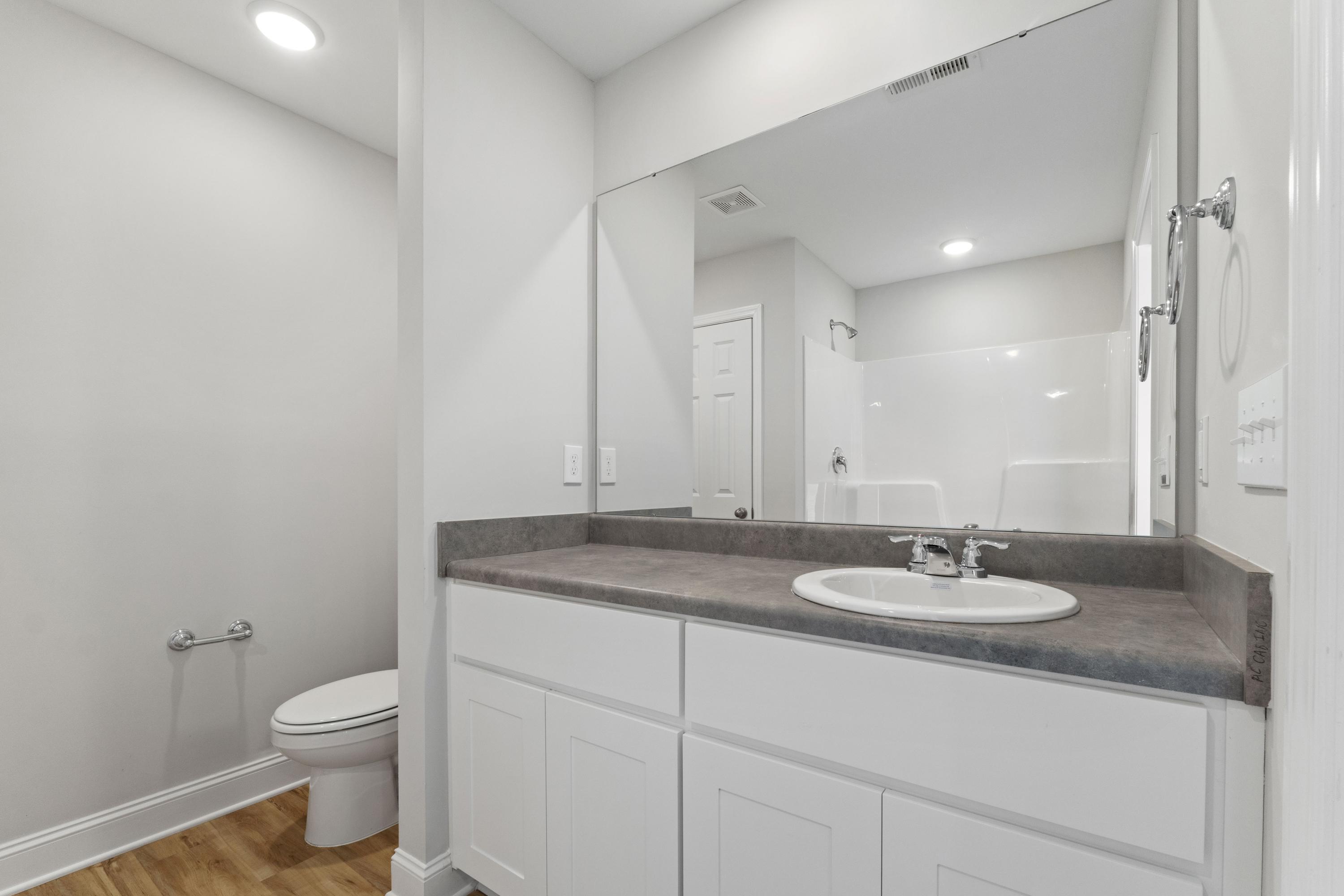 Spacious white bathroom in Chapel Hill Athens AL with double vanity, large mirror, walk-in shower, and recessed lighting