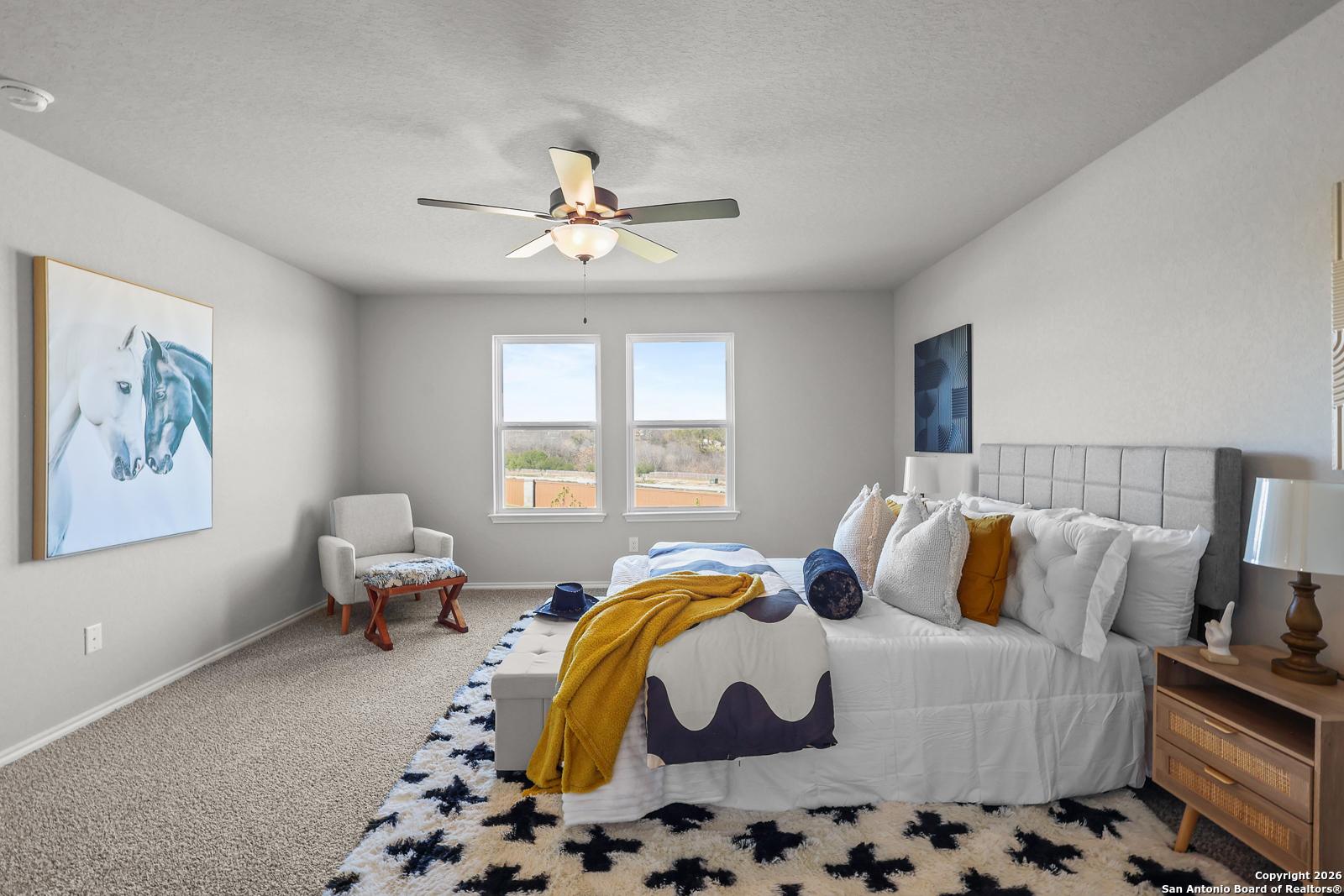 Spacious bedroom with king bed, ceiling fan, large windows, abstract art, and modern accents in Davidson Homes The Murray K, San Antonio