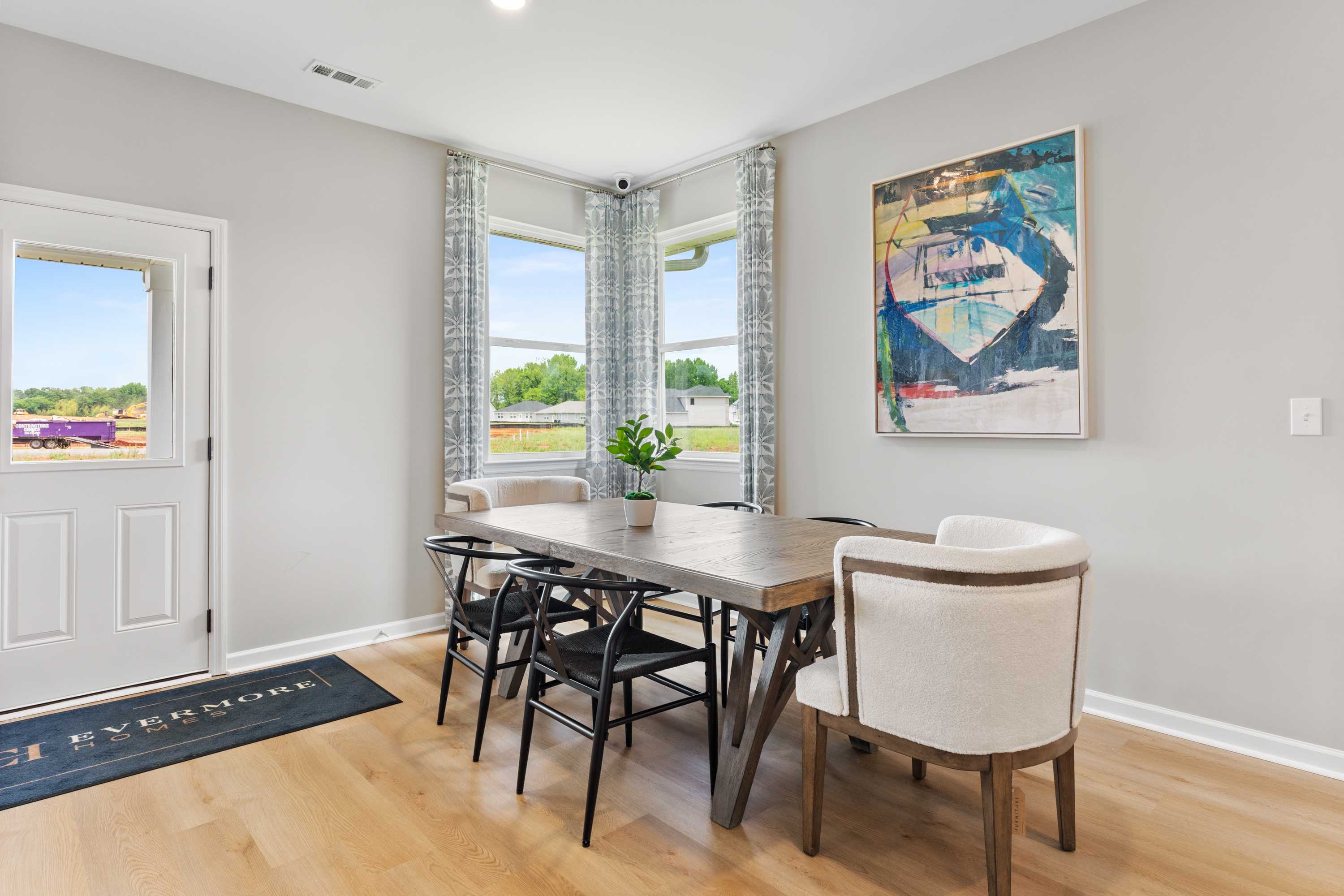 Modern dining room in Forest Glen Hazel Green Alabama with wooden table black chairs large corner windows and abstract wall art