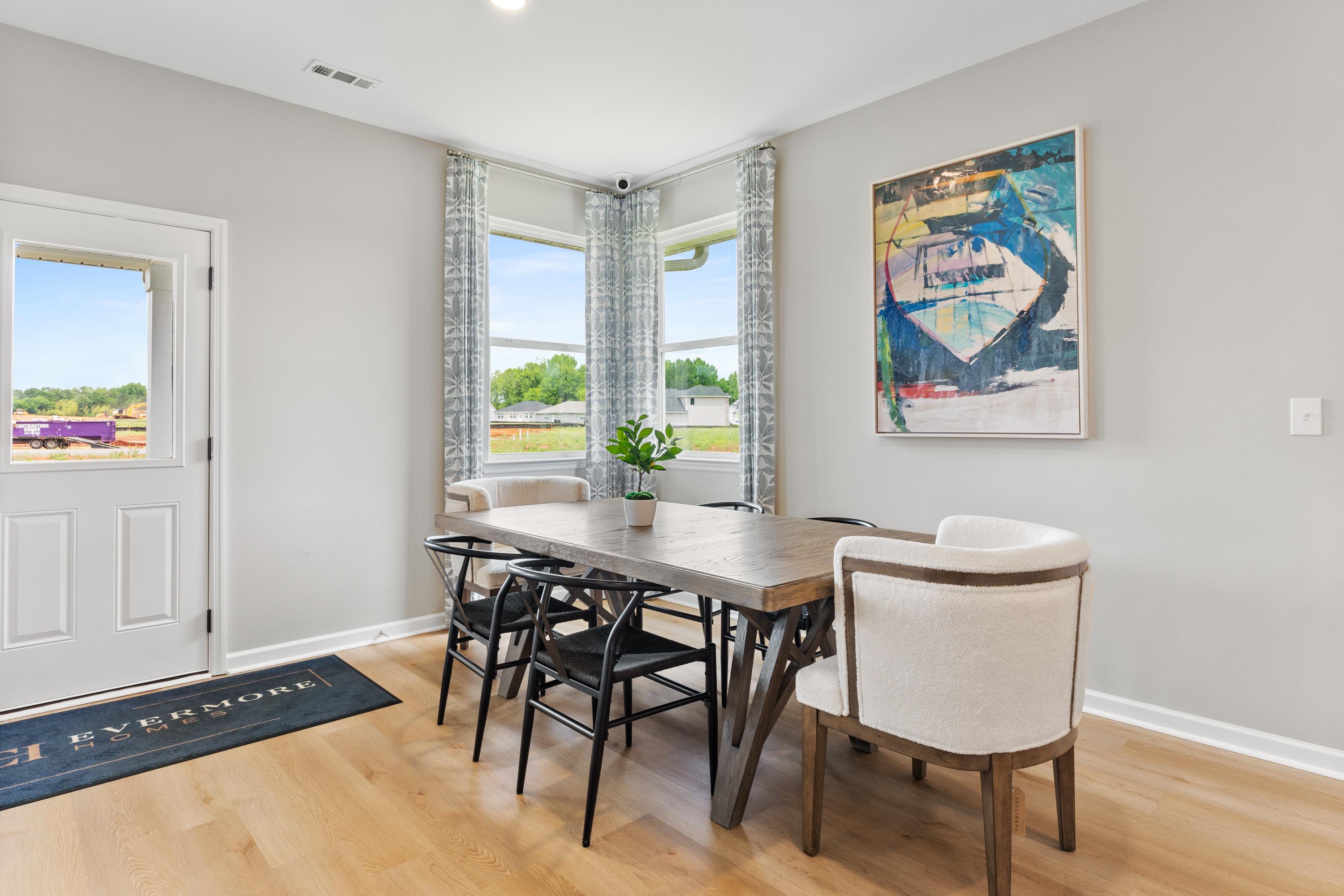 Modern dining room in Forest Glen Hazel Green Alabama with wooden table black chairs large corner windows and abstract wall art