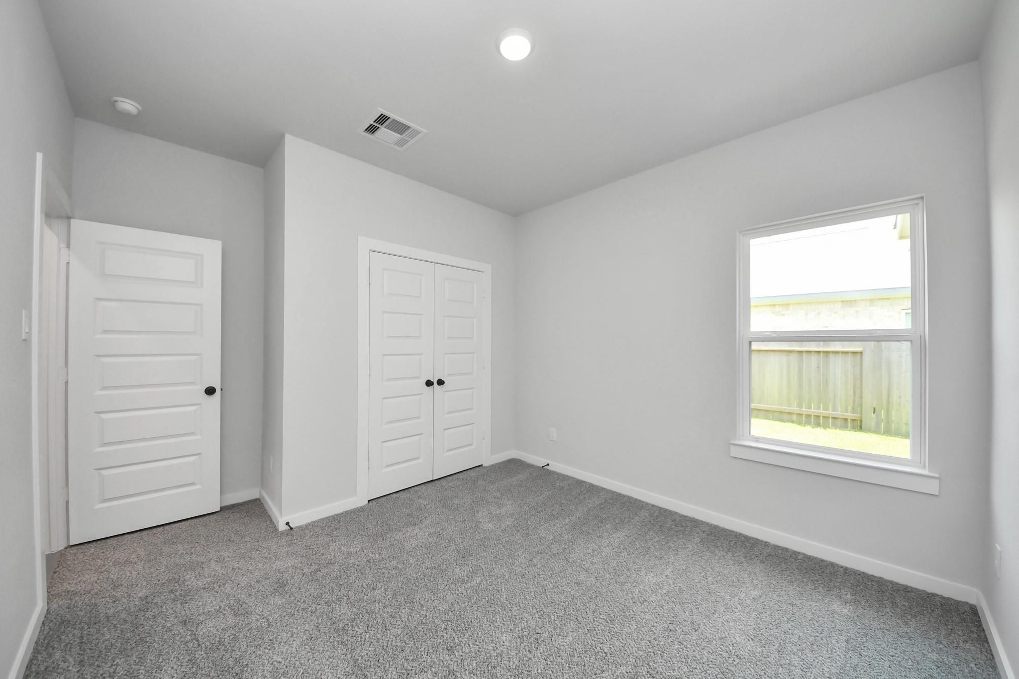Bright, carpeted secondary bedroom with closet in The Riviera C floor plan at River Ranch Meadows, Dayton, Texas.