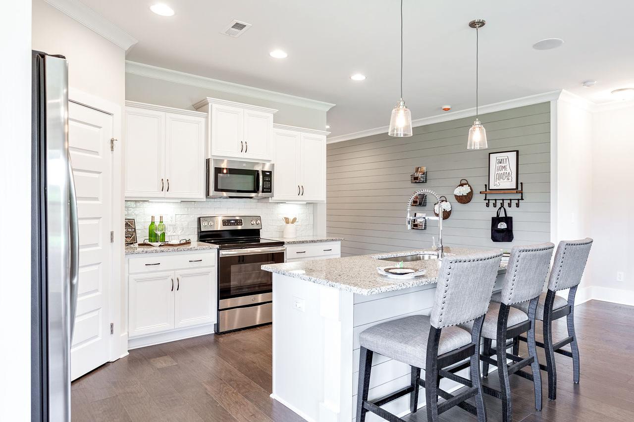 Modern white kitchen in Williams Pointe Huntsville AL with shaker cabinets, stainless appliances, quartz island, and hardwood floors