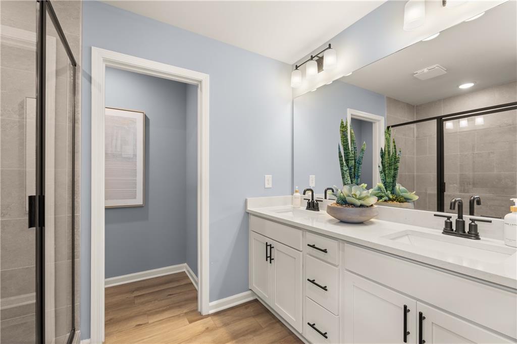 Elegant master bathroom featuring double white vanity, light blue walls, glass shower, and plants in Davidson Homes The Burton C, Canton, GA