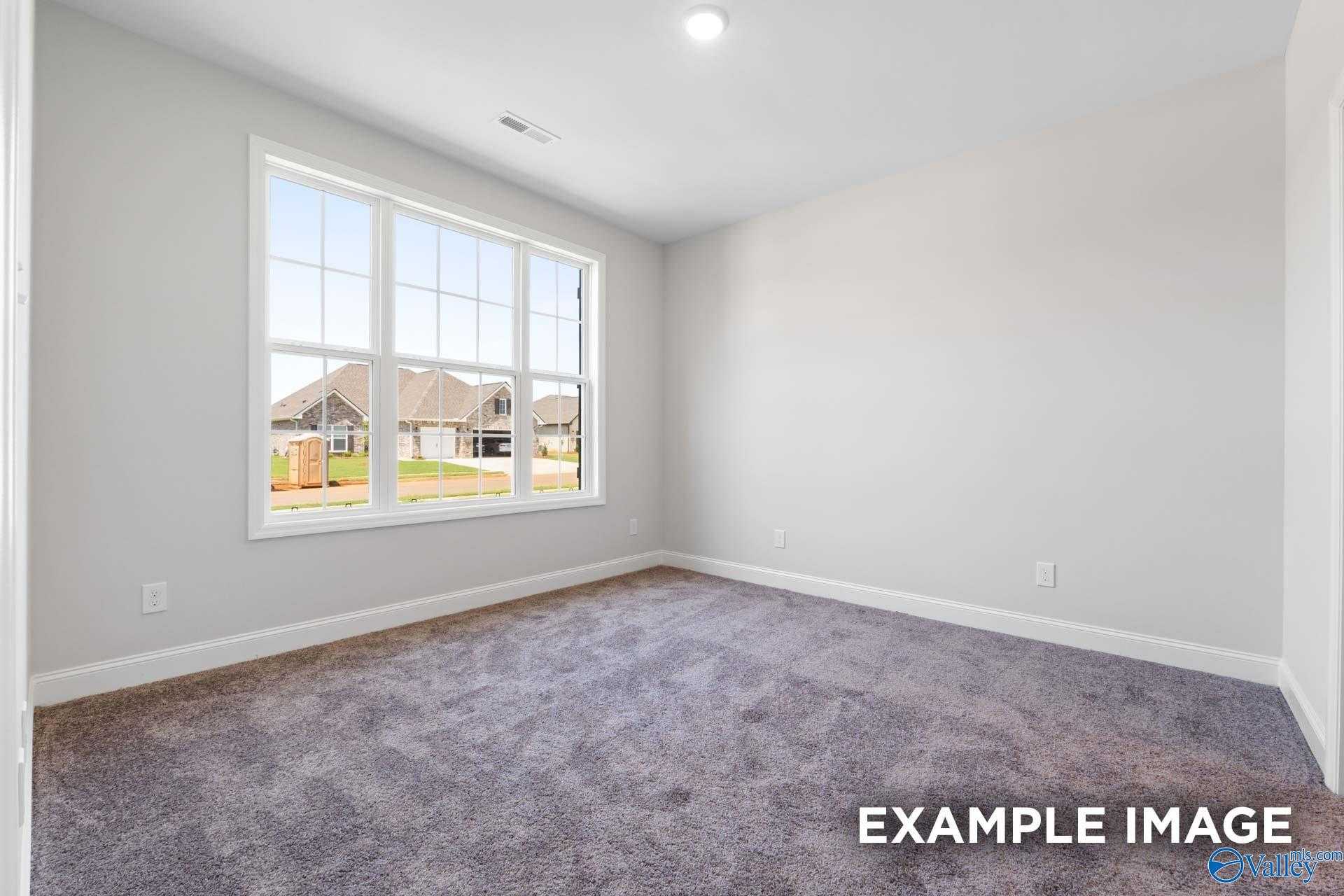 Bright empty bedroom with large window overlooking neighborhood, gray walls, carpeted floor in The Lanier home, Meridianville, Alabama