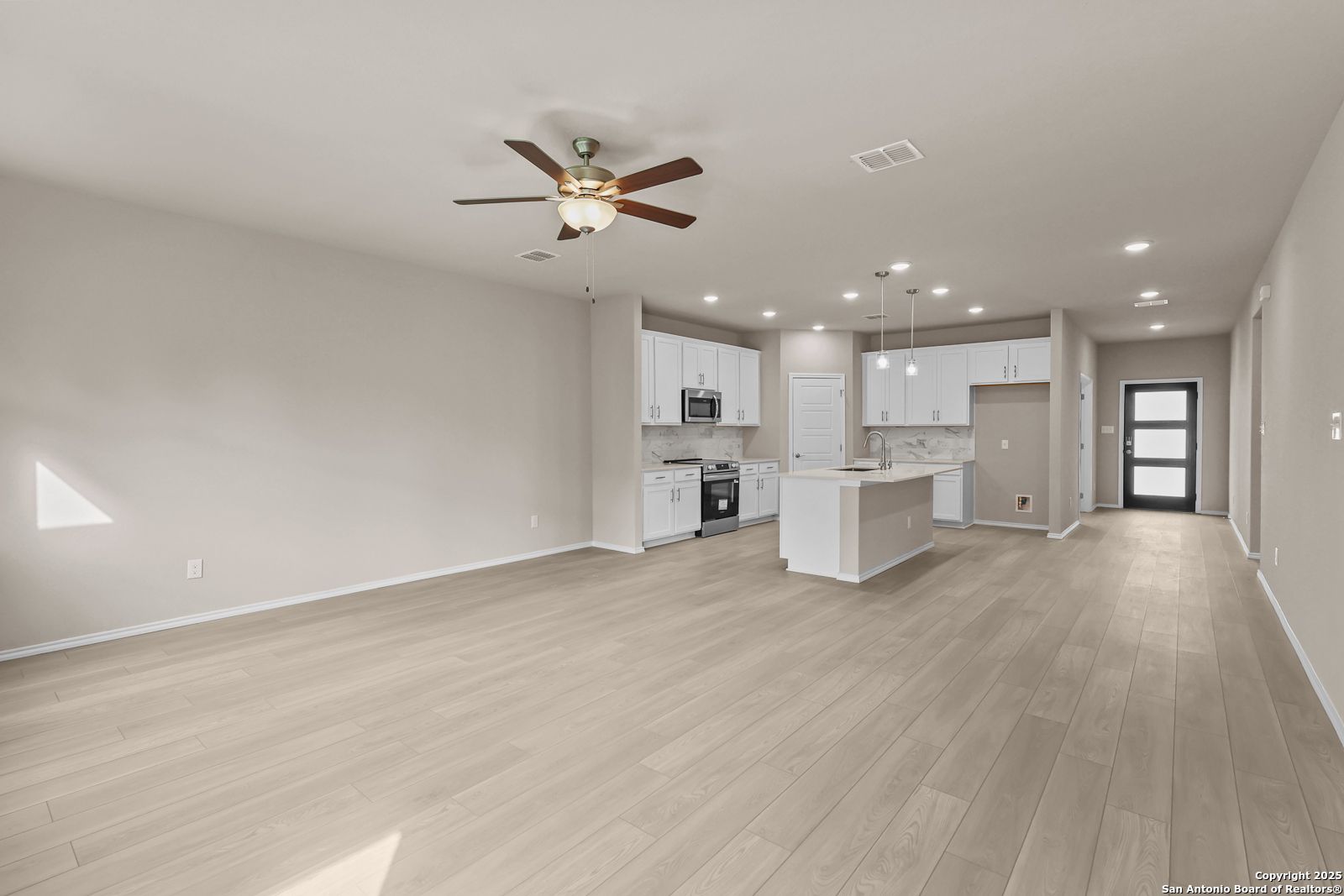 Spacious open kitchen with white cabinets, stainless appliances, and large island in Davidson Homes Douglas G, San Antonio