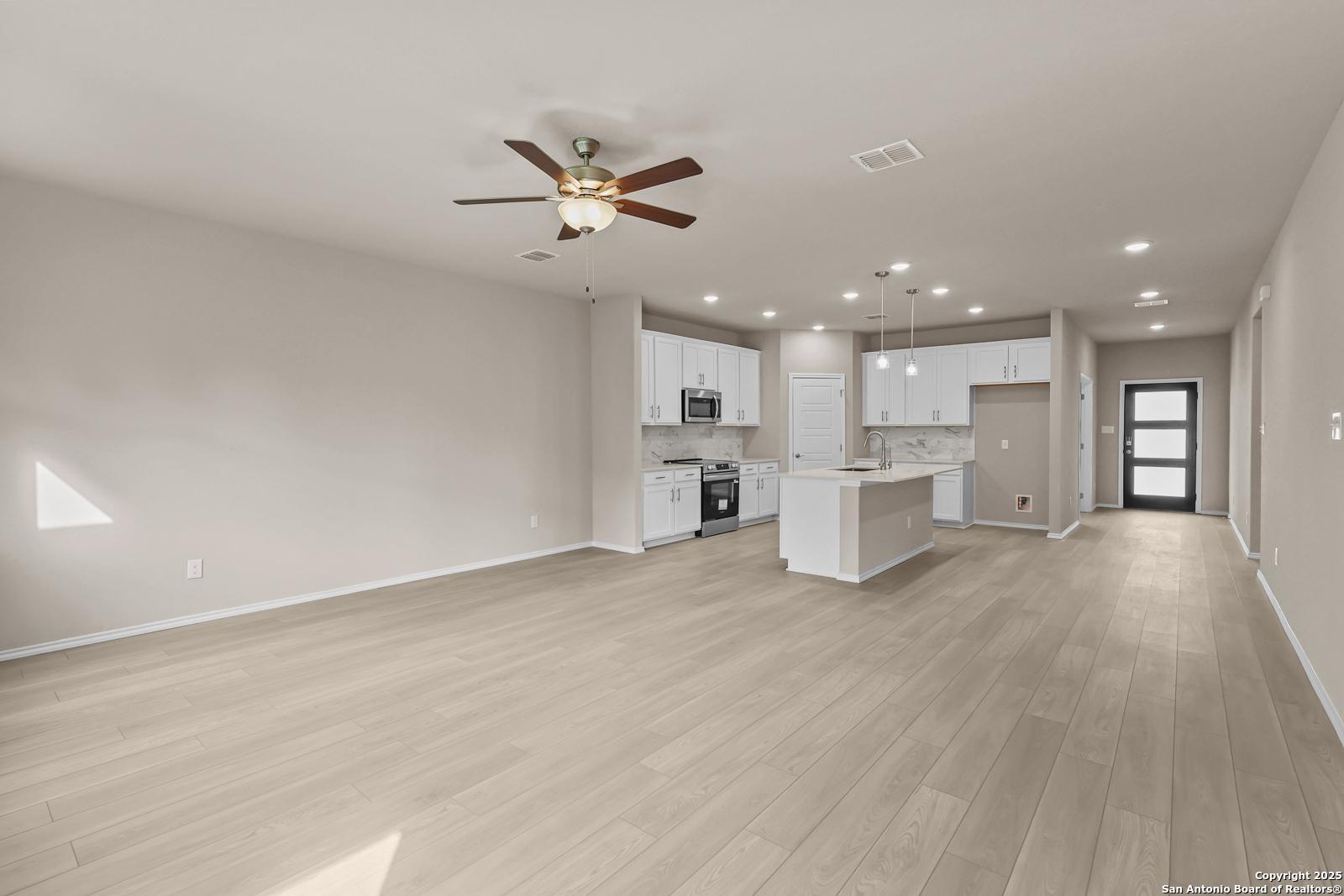 Spacious open kitchen with white cabinets, stainless appliances, and large island in Davidson Homes Douglas G, San Antonio