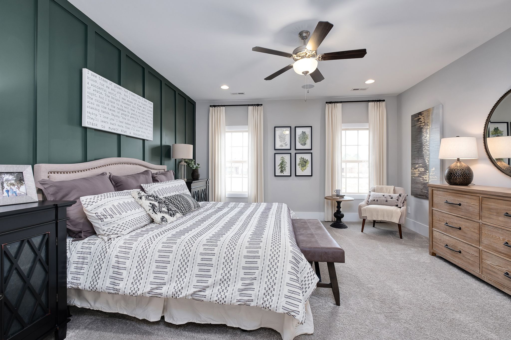 Spacious master bedroom in Chimney Creek, Hampton Cove Alabama with sage green accent wall, king bed, and ceiling fan