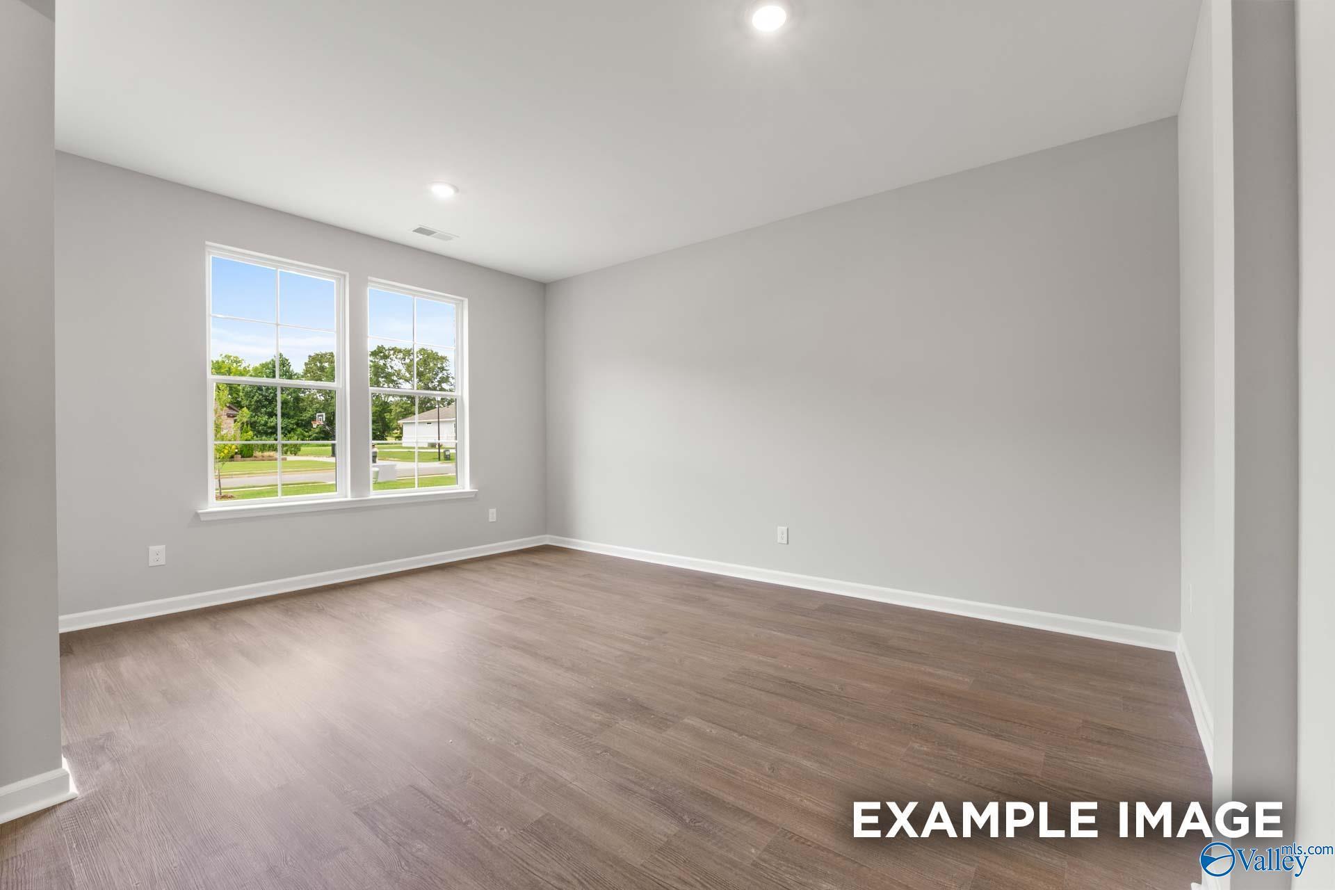 Bright secondary bedroom with hardwood floors, large windows, and green lawn view in Evermore Homes The Avalon D, Owens Cross Roads