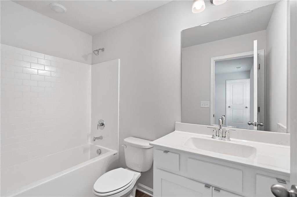 Bright white subway tile bathroom with tub-shower combo, vanity, and mirror in Davidson Homes The Hickory B, Winder, GA