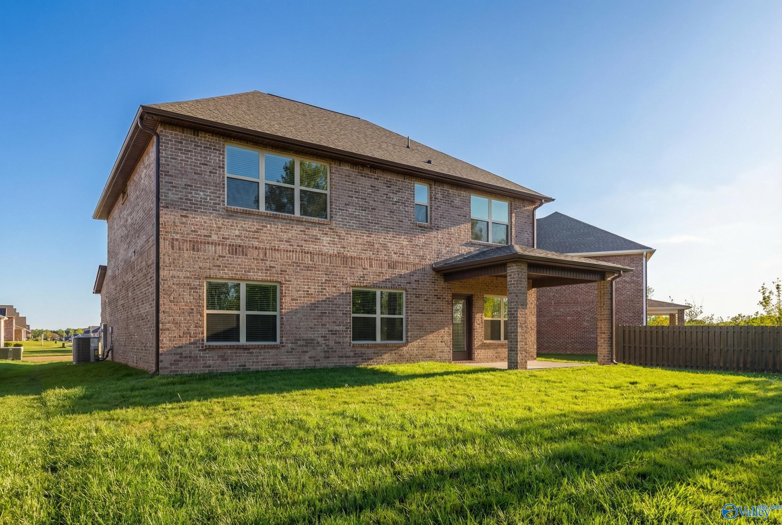 Two-story brick 4-bedroom home with 2-car garage, covered patio, and lush green yard in Ricketts Farm, Athens, Alabama