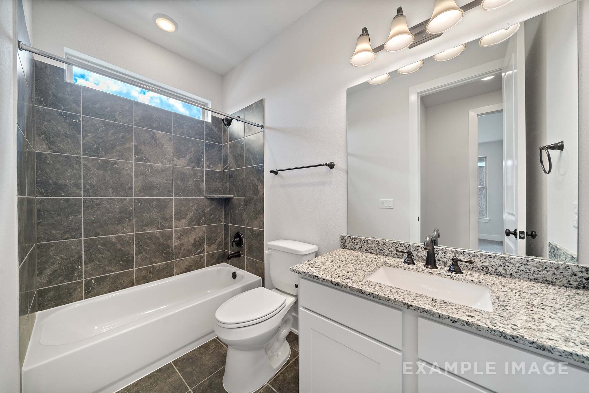 Modern bathroom in The Victoria by Davidson Homes with granite vanity, tiled tub shower, and oil-rubbed bronze fixtures