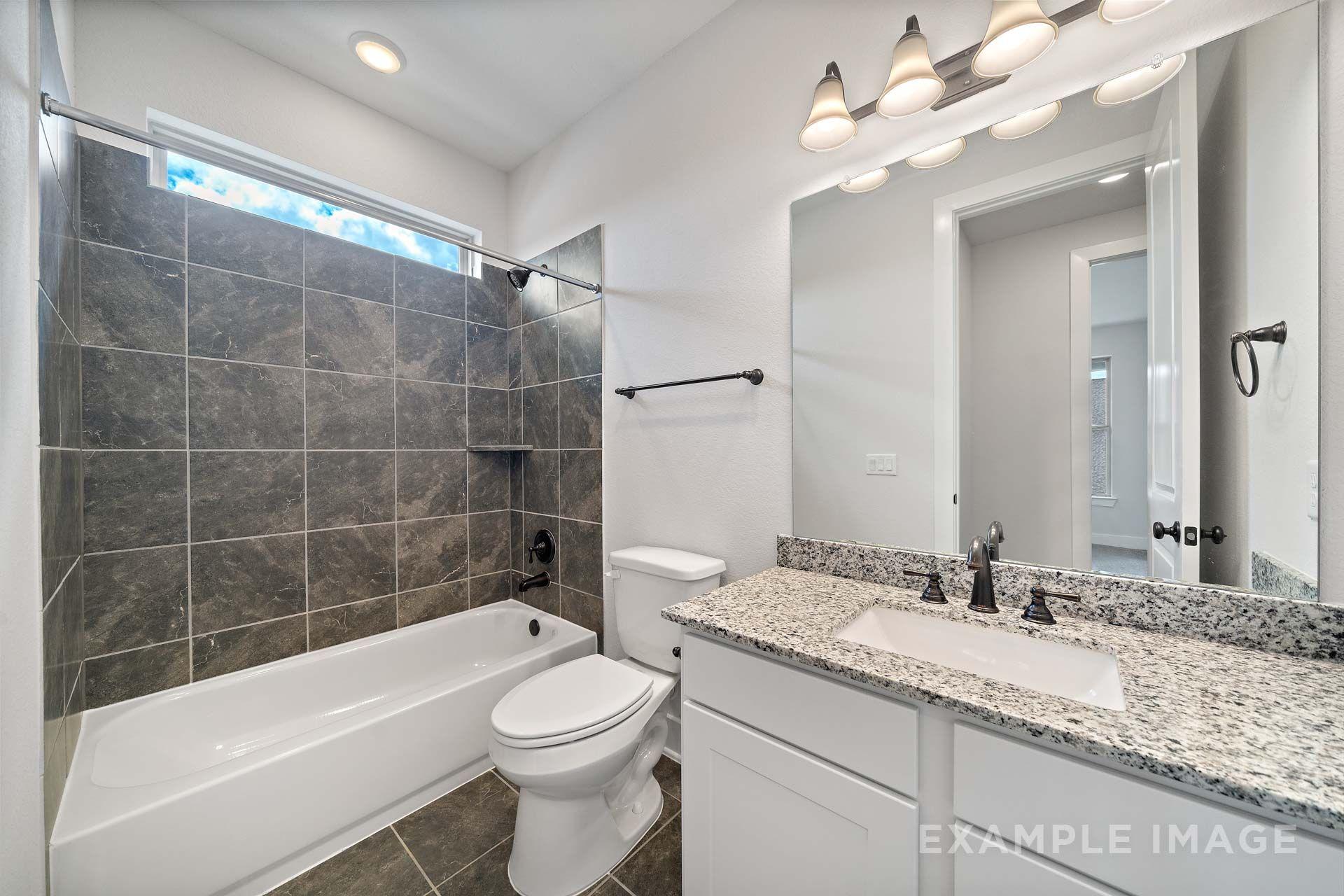 Modern bathroom in The Victoria by Davidson Homes with granite vanity, tiled tub shower, and oil-rubbed bronze fixtures