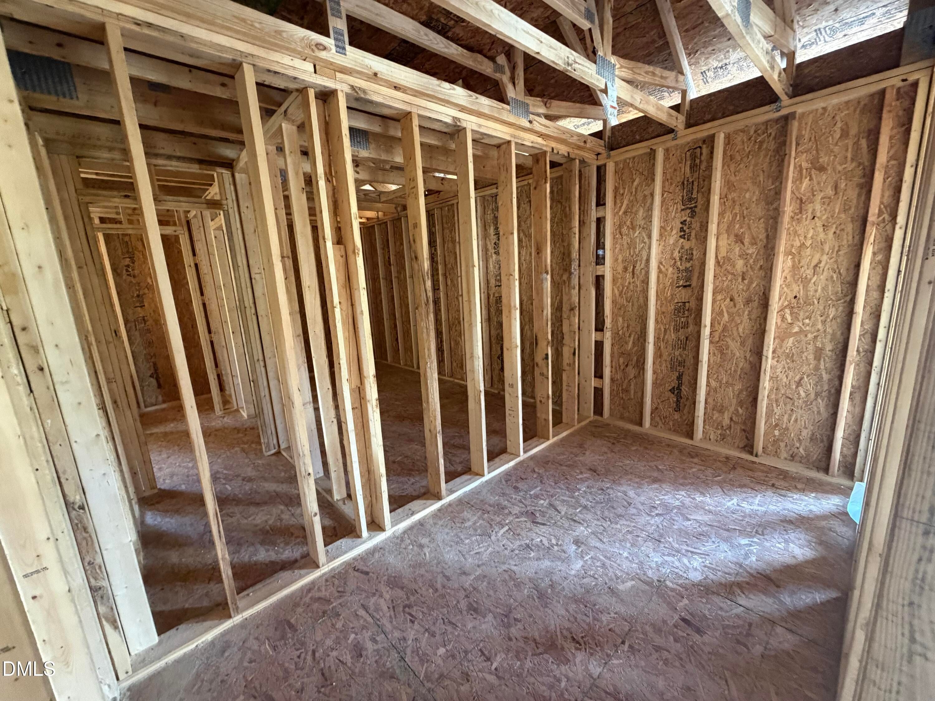Framed interior with wooden studs, plywood sheathing, and open room layout in The Hickory II C home by Davidson Homes, Lillington, NC