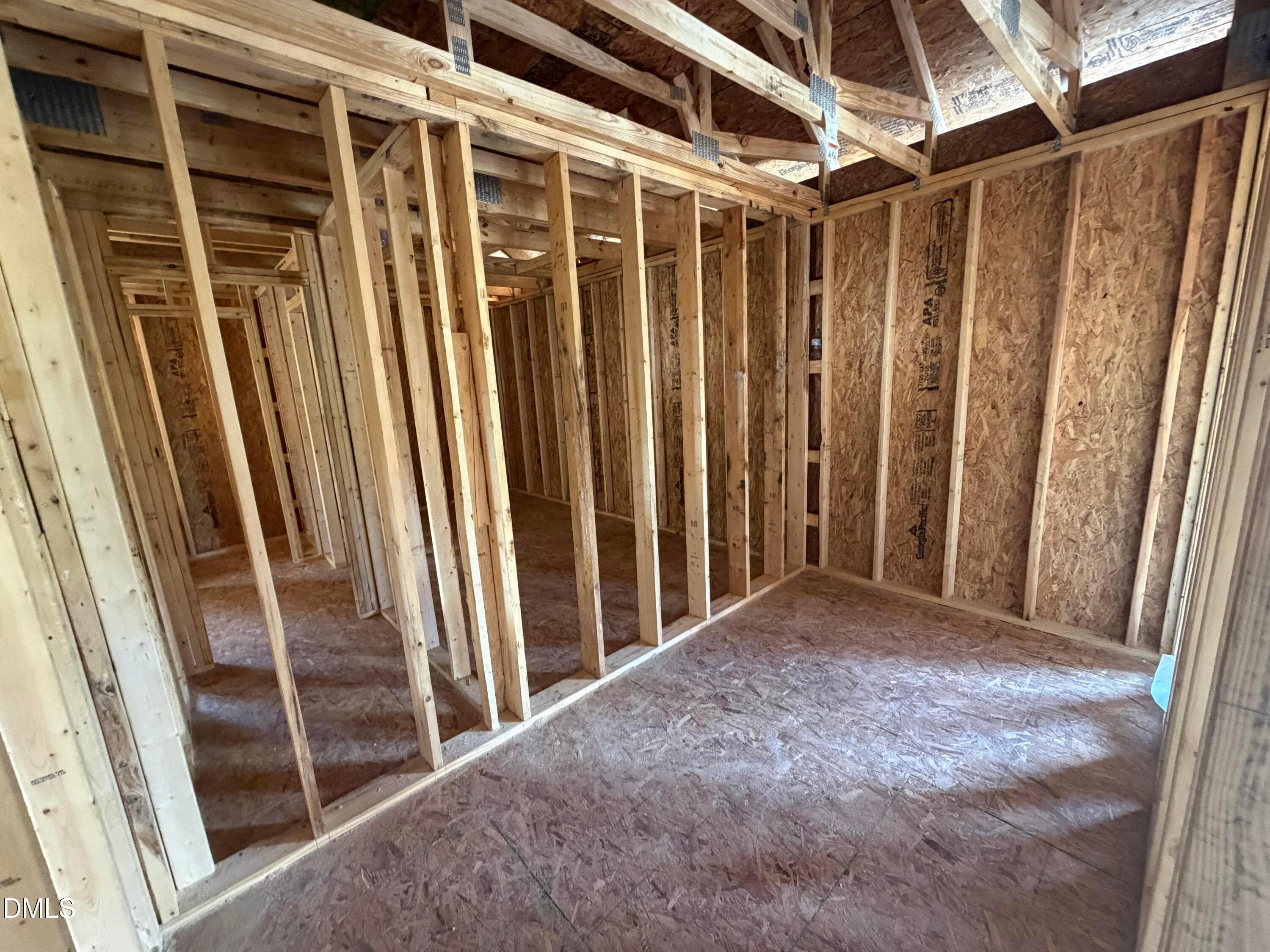 Framed interior with wooden studs, plywood sheathing, and open room layout in The Hickory II C home by Davidson Homes, Lillington, NC