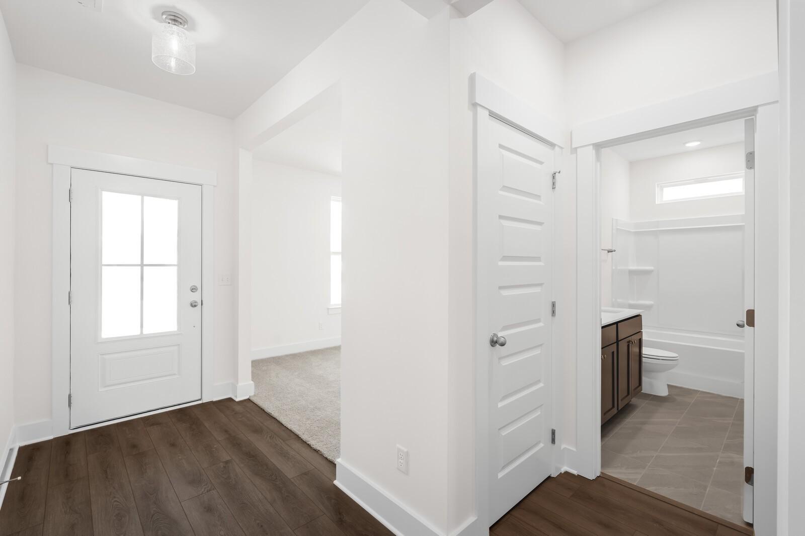 Bright foyer with glass-panel front door, hardwood floors, and full bath with tub in Davidson Homes Cottonwood E, Gallatin TN