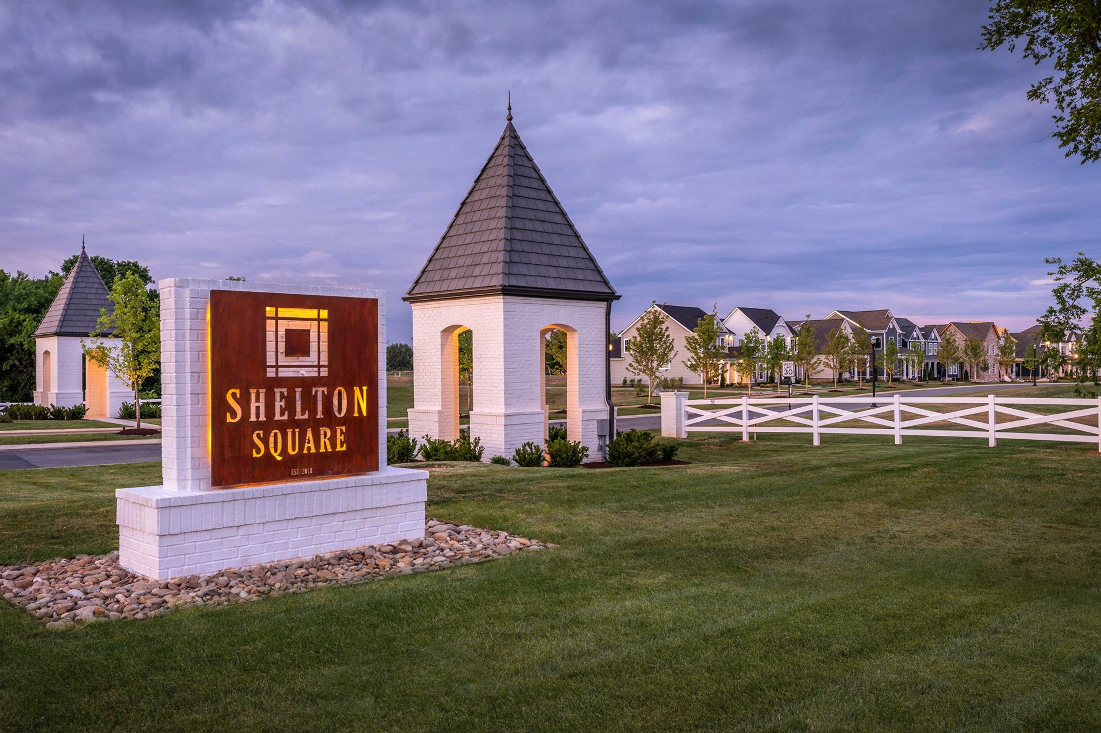 Shelton Square entrance sign in Murfreesboro TN with white pavilion, picket fence, and new homes at dusk