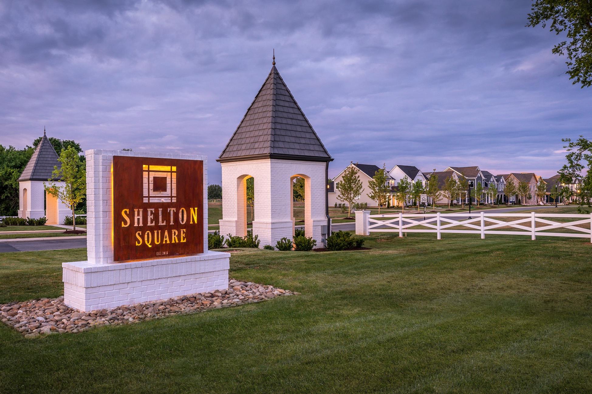 Shelton Square entrance sign in Murfreesboro TN with white pavilion, picket fence, and new homes at dusk