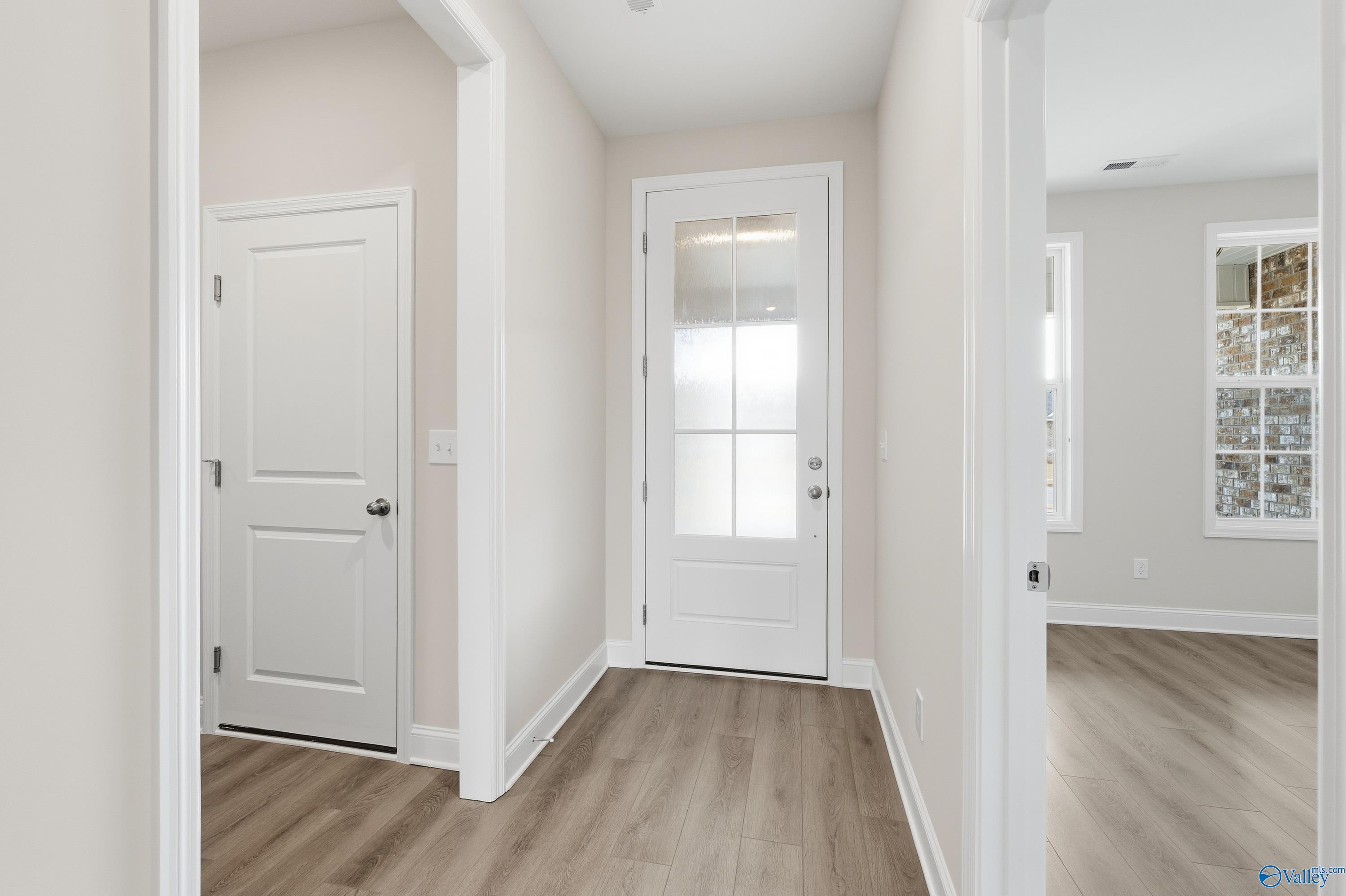 Bright hallway with white doors, frosted glass entry, and light wood floors in Davidson Homes The Rockford, Meridianville AL