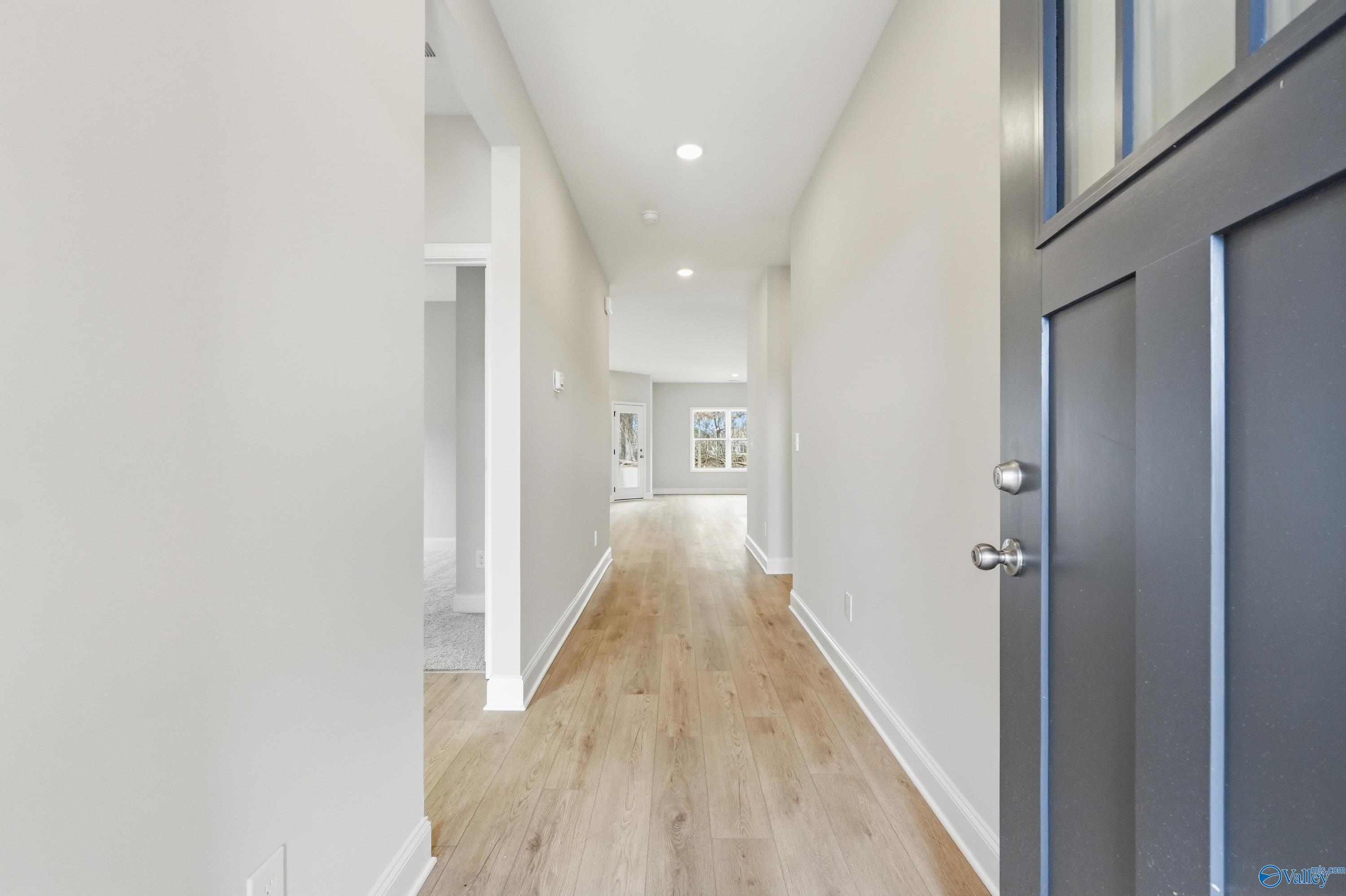 Bright entry hallway with light oak floors, white walls, and black glass-front door in Davidson Homes The Franklin, Meridianville AL