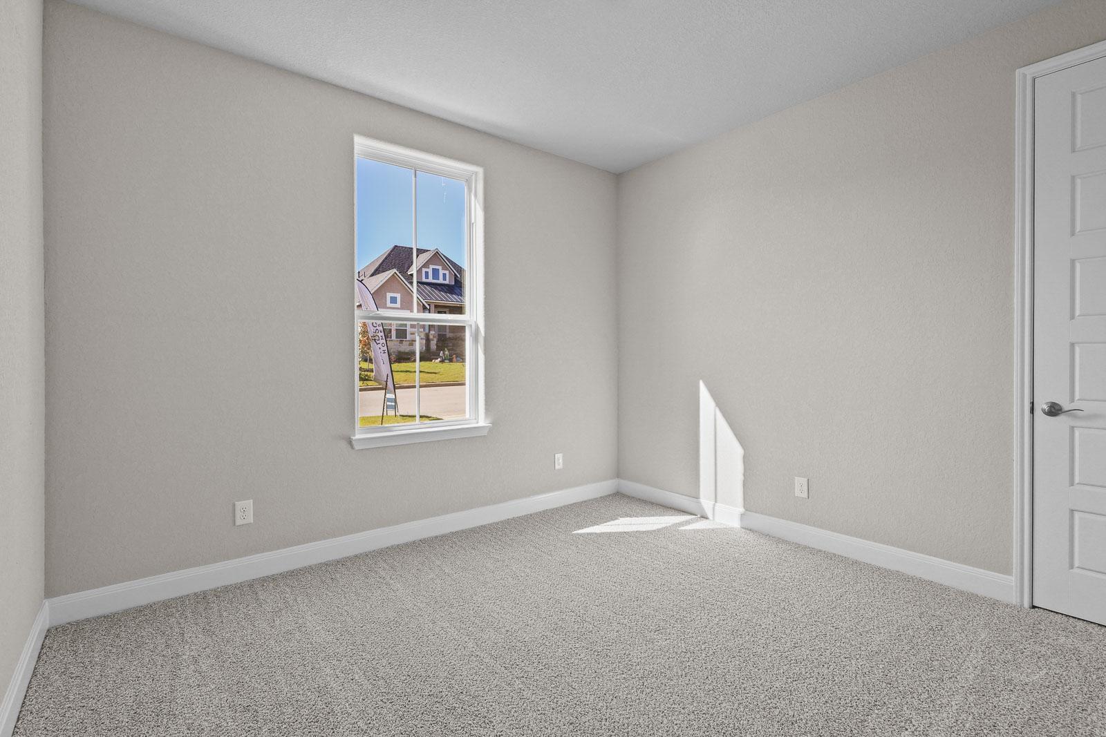Spacious secondary bedroom in The Jennings F floor plan with neutral carpet, natural light, and classic interior finishes.