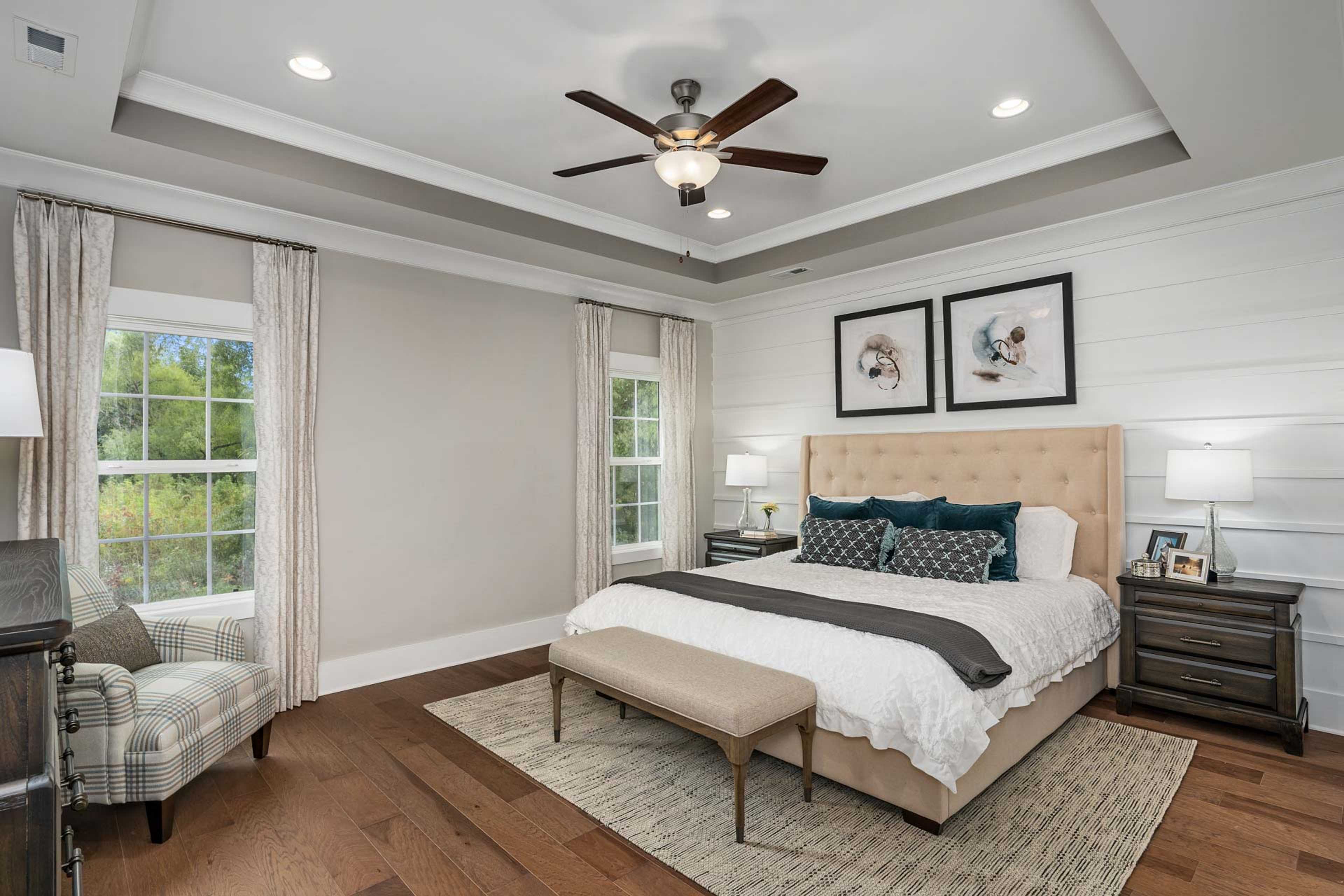 Primary bedroom at Kendall Downs in Toney Alabama with king bed, hardwood floors, ceiling fan, and dog artwork