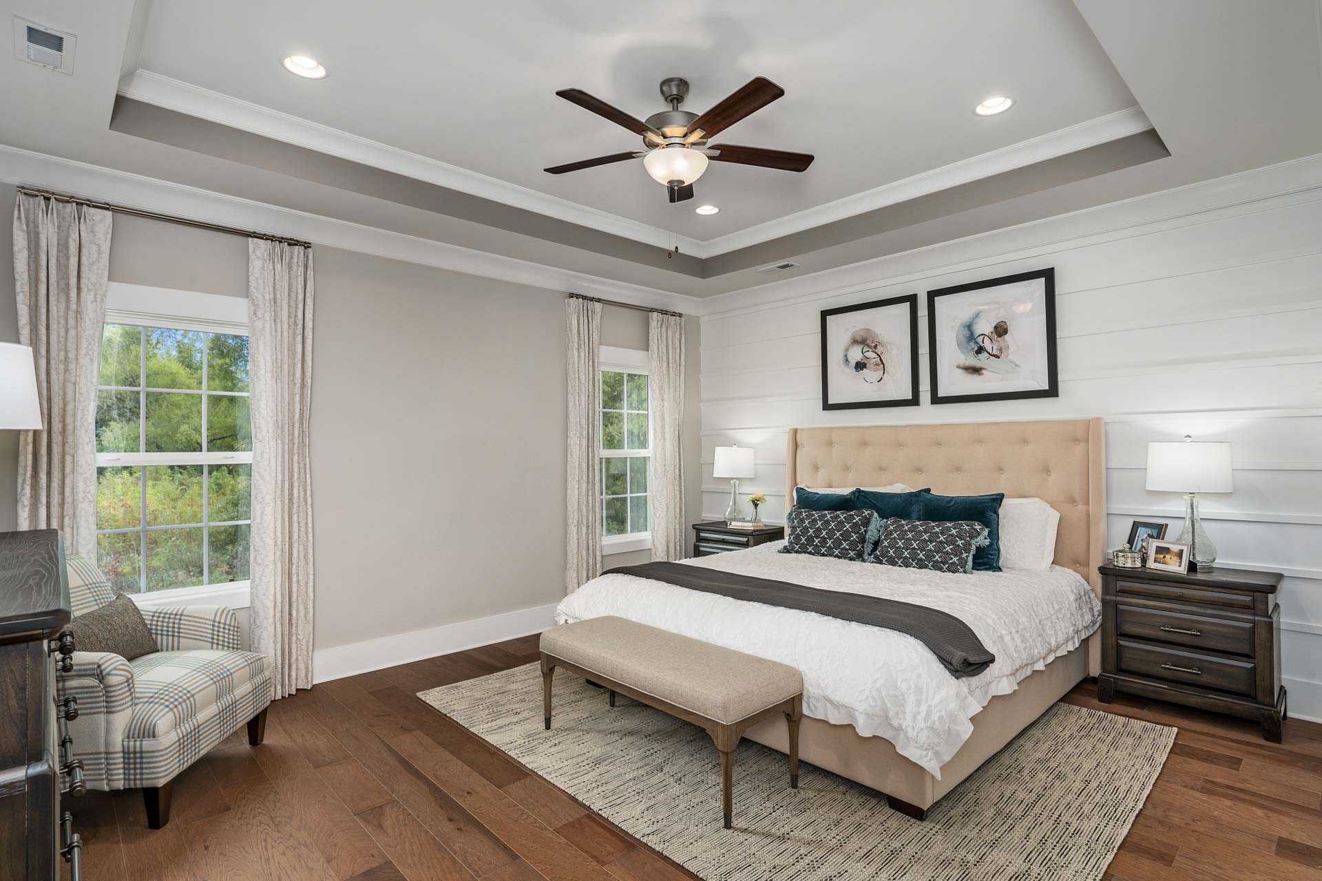 Primary bedroom at Kendall Downs in Toney Alabama with king bed, hardwood floors, ceiling fan, and dog artwork