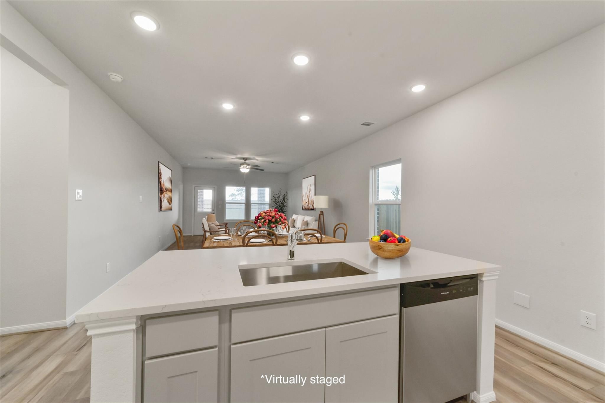 Open-concept kitchen with white island sink, dishwasher, and cabinets, adjacent dining area with table in The San Marcos E by Davidson Homes, Beasley, TX
