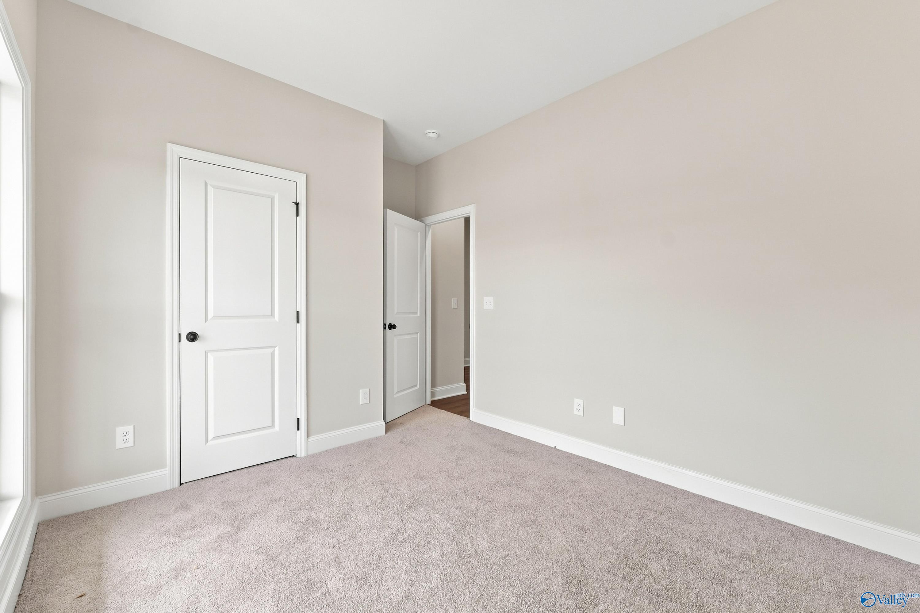 Bright, neutral-toned secondary bedroom with plush carpet in The Asheville E floor plan by Davidson Homes, Hazel Green, AL.
