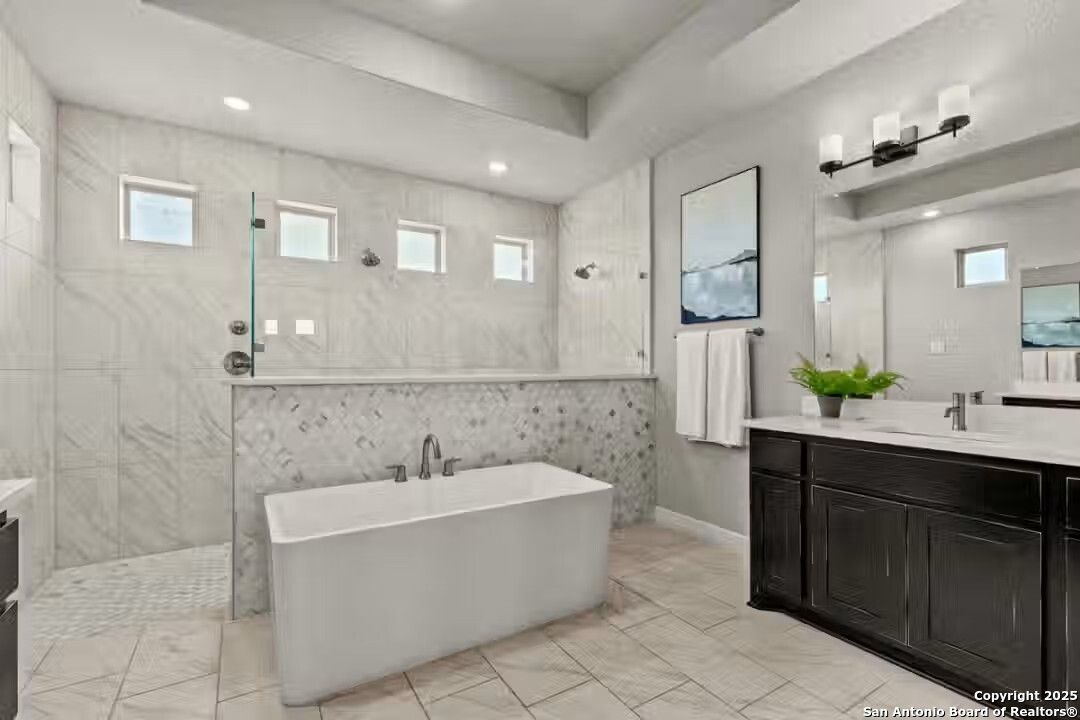 Luxurious marble master bathroom with freestanding tub, glass shower, and double vanity in Davidson Homes The Summerlin B, Castroville, Texas