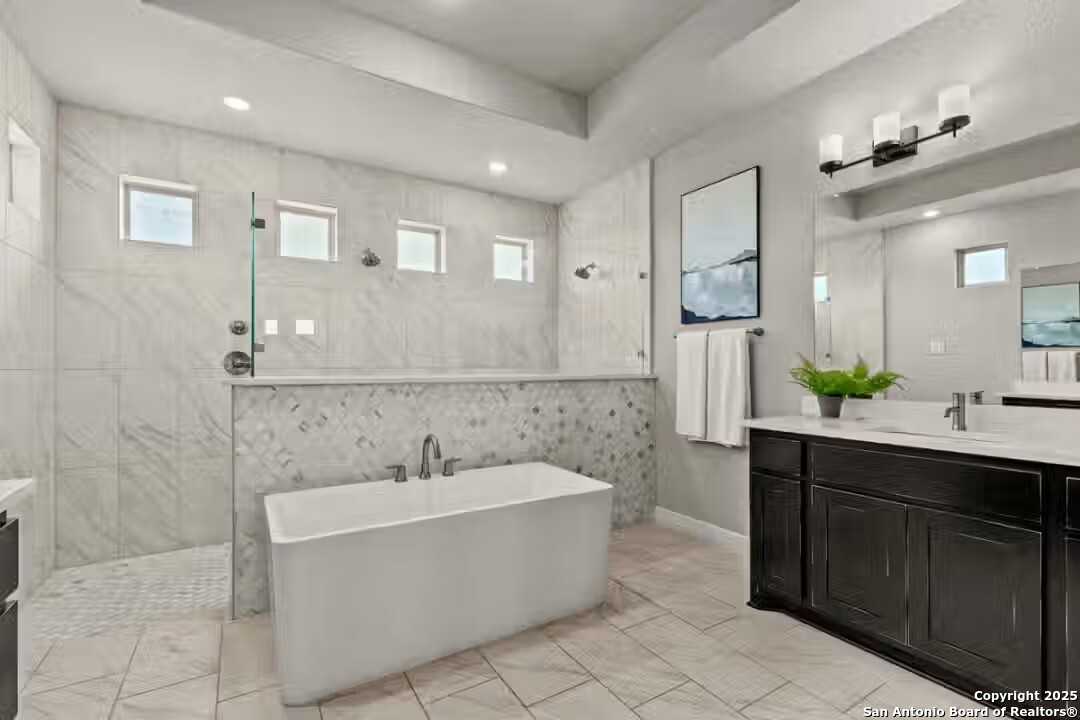 Luxurious marble master bathroom with freestanding tub, glass shower, and double vanity in Davidson Homes The Summerlin B, Castroville, Texas