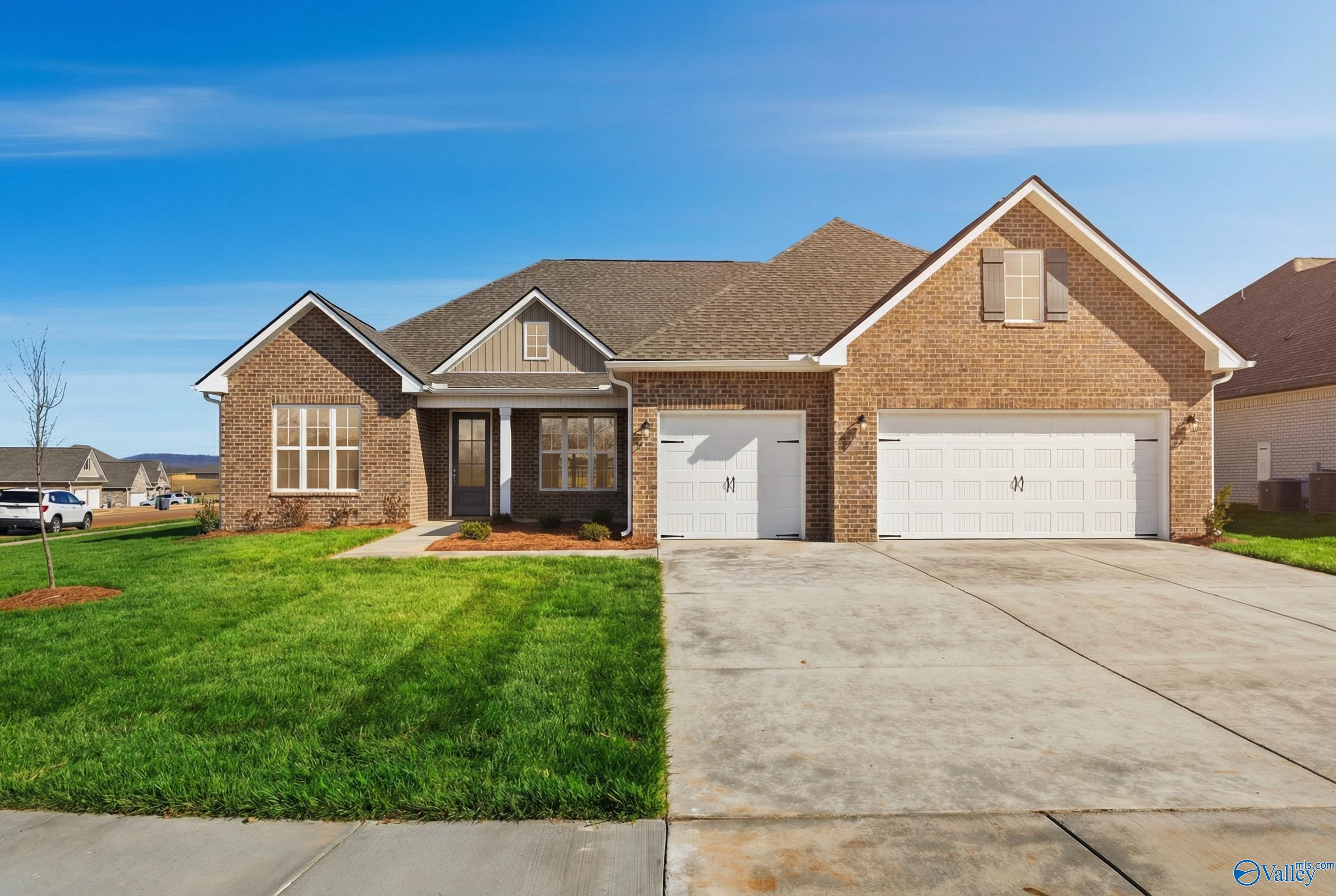 Single-story brick home with 2-car garage, driveway, and lush green lawn in Creekside, Harvest, Alabama