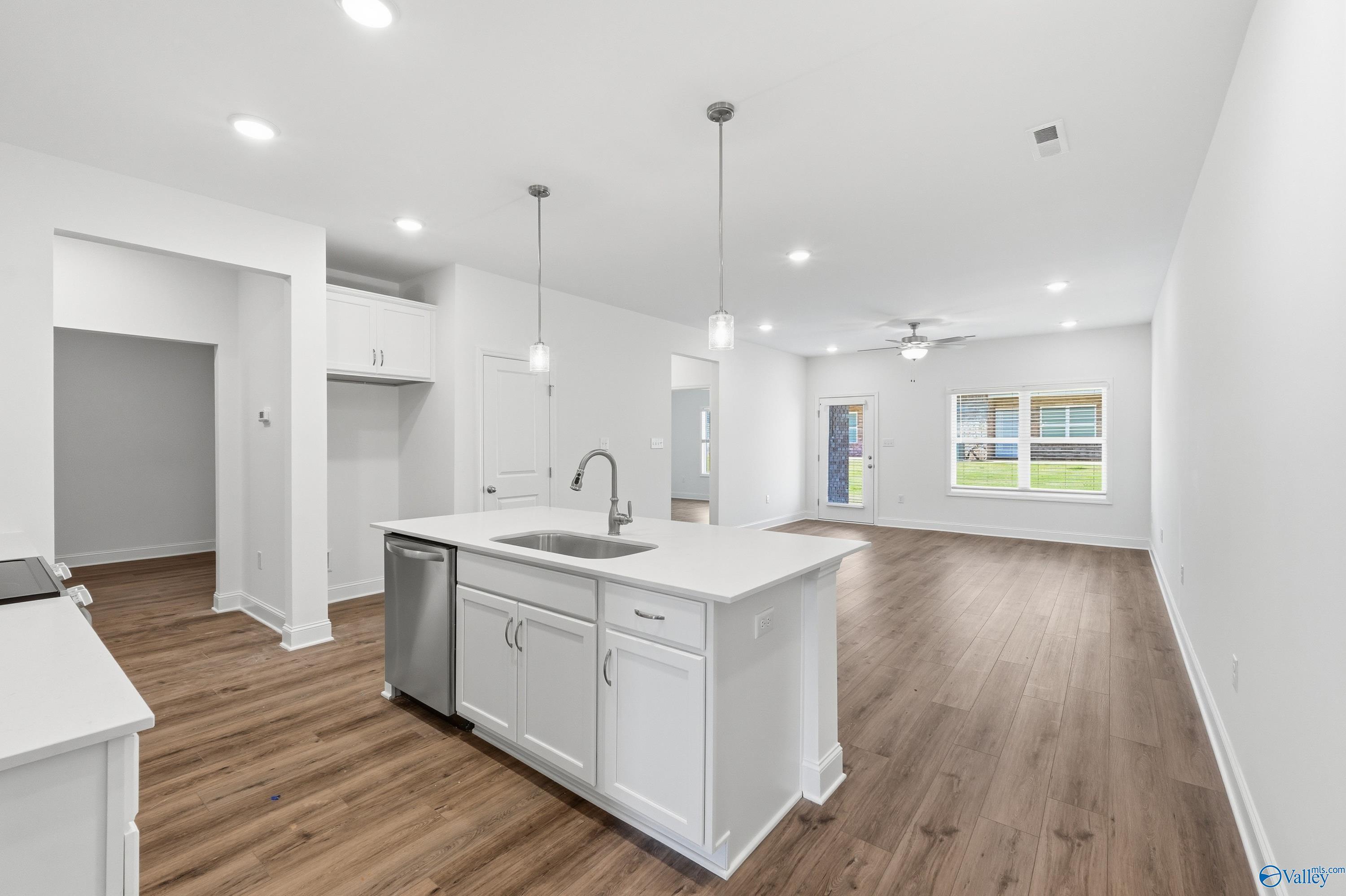 Modern open-concept kitchen with white island, stainless dishwasher, sink, and hardwood floors in Cumberland D home, Decatur AL