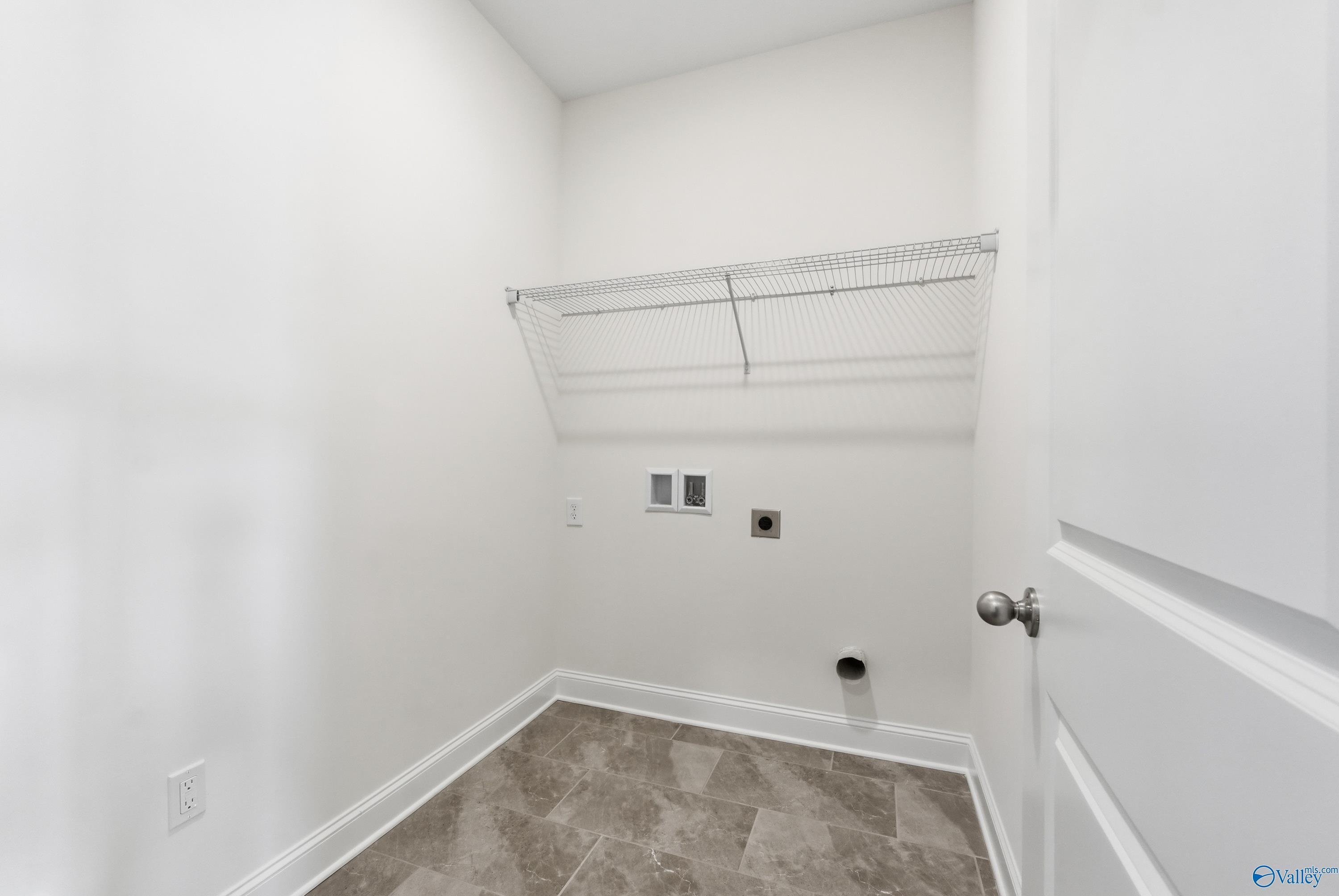Spacious laundry room with wire shelving, washer-dryer hookups and tiled floor in Davidson Homes Montgomery C, Creekside, Harvest, AL
