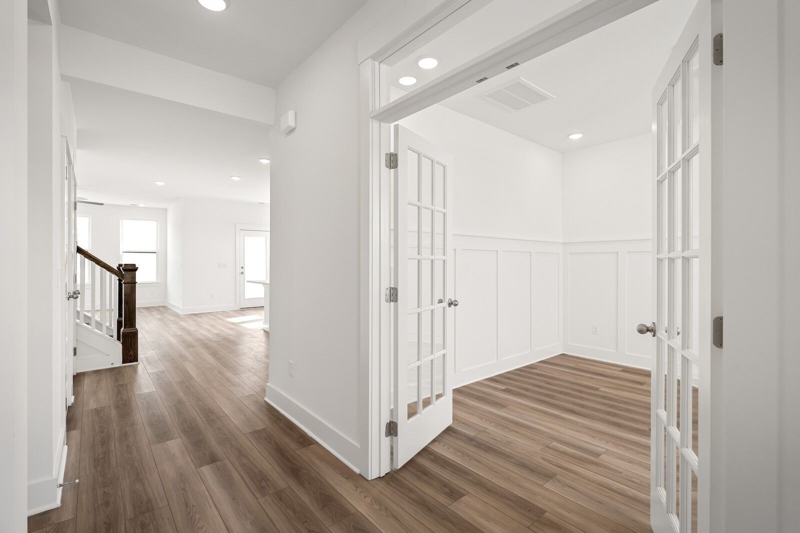 Elegant white foyer with open French doors to study, hardwood floors, and staircase in Davidson Homes The Ash C, Mt. Juliet