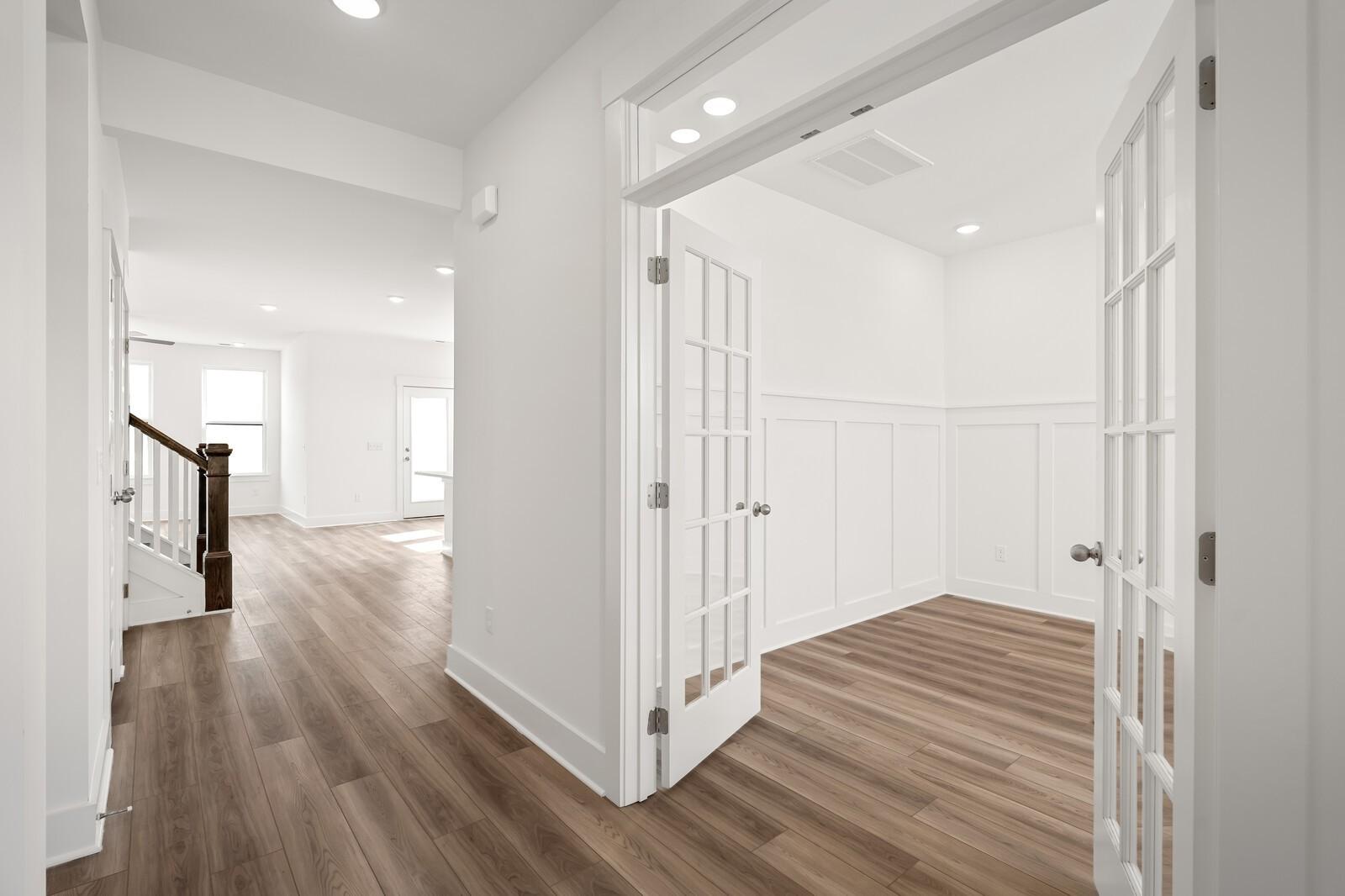 Elegant white foyer with open French doors to study, hardwood floors, and staircase in Davidson Homes The Ash C, Mt. Juliet