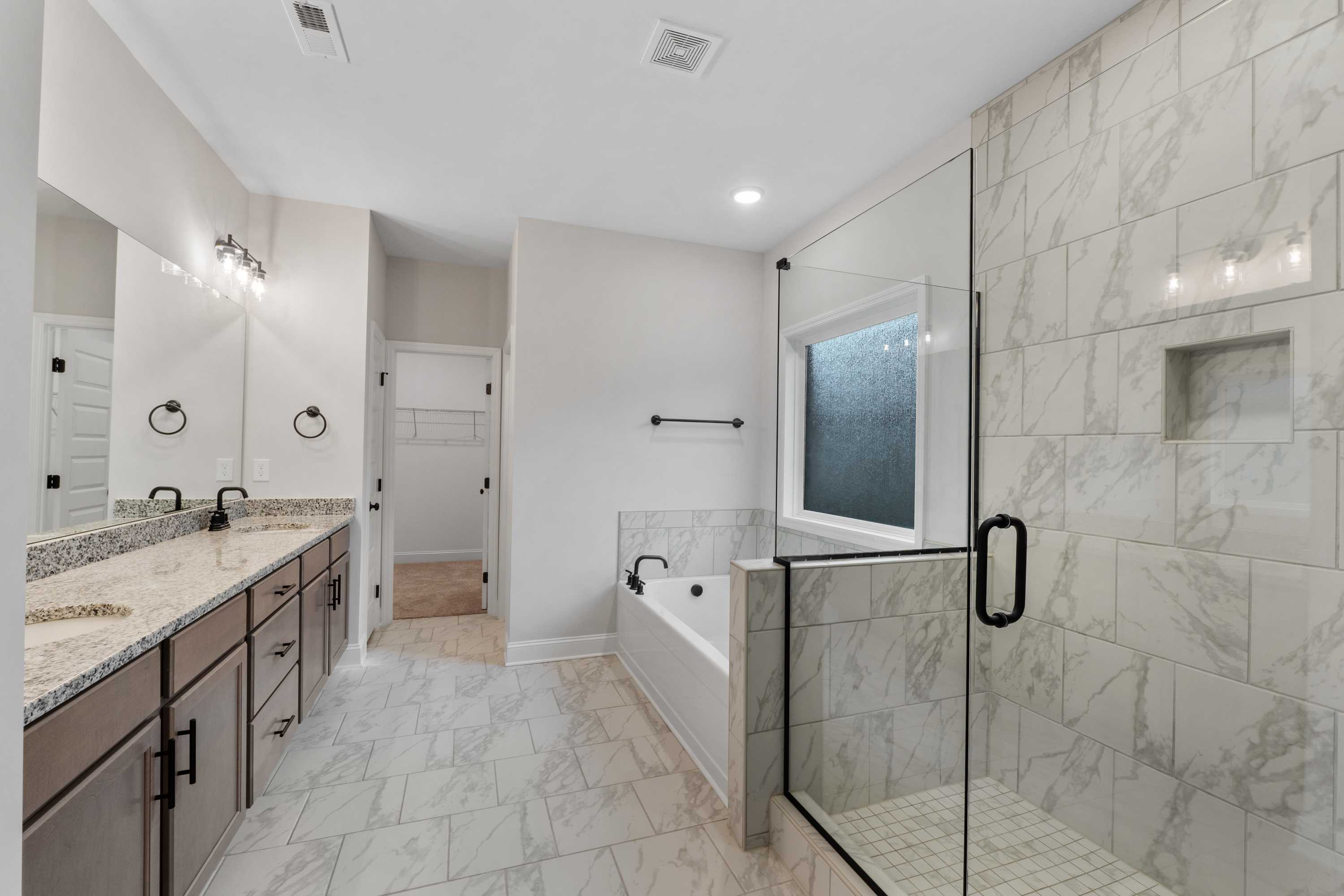 Luxurious master bathroom in The Oxford with double vanity, soaking tub, and frameless glass shower
