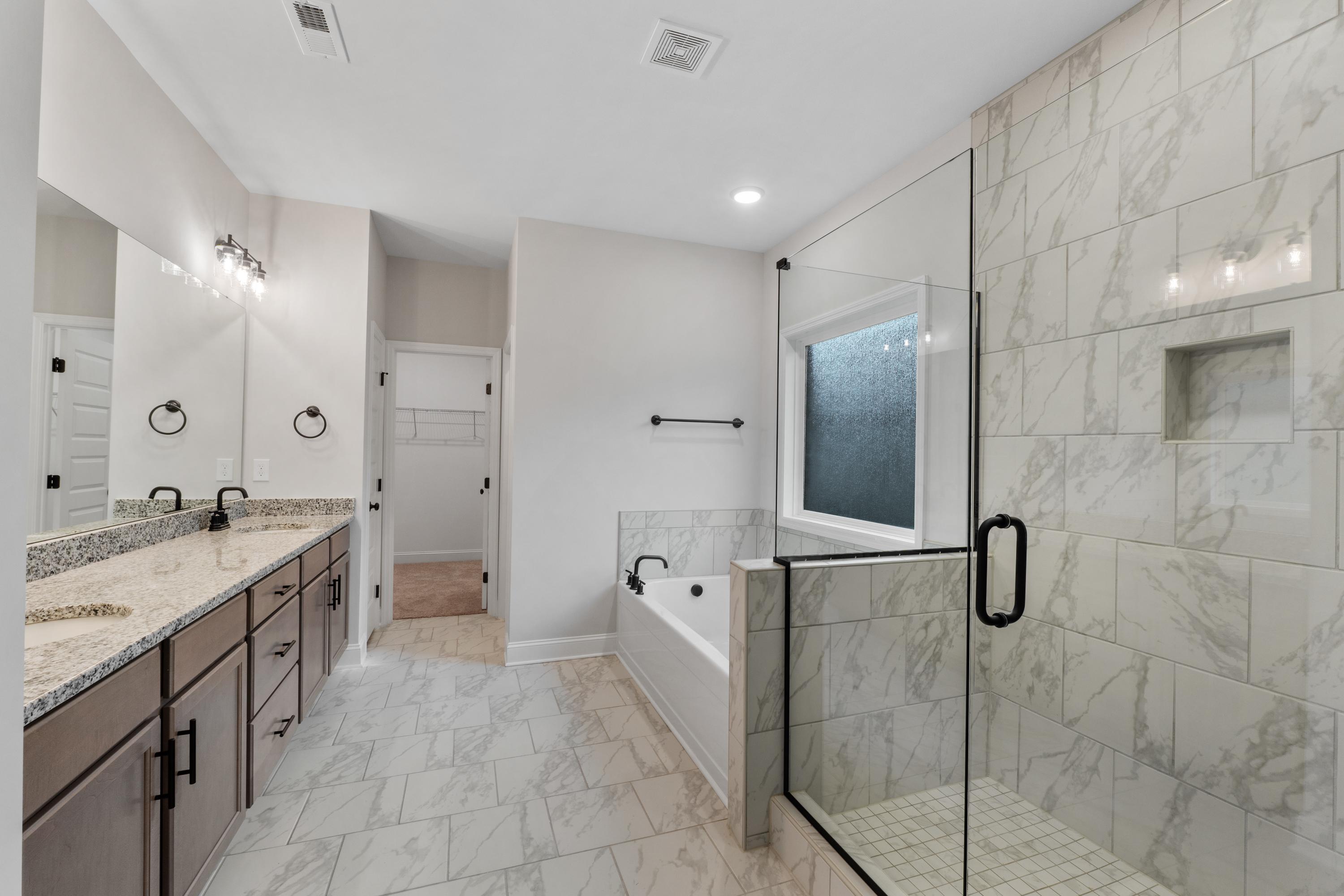 Luxurious master bathroom in The Oxford with double vanity, soaking tub, and frameless glass shower