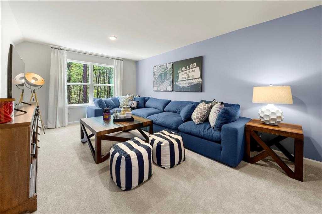Cozy blue sectional sofa with poufs and pillows in spacious bonus room, large windows to wooded view, Davidson Homes The Hickory B, Riverwood, Dallas, GA