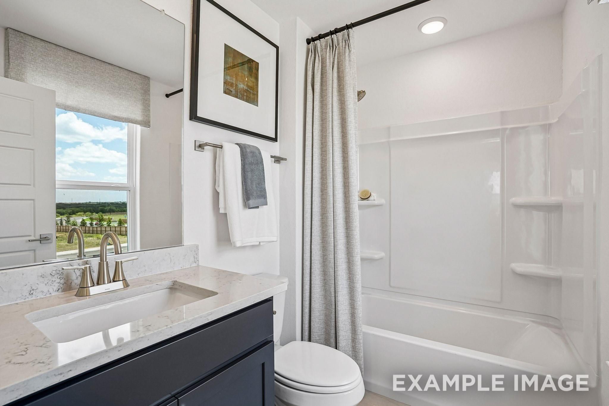 Modern bathroom with navy vanity, quartz countertop, and tub shower in Davidson Homes Ashport J plan, Sundance Cove, Crosby, TX