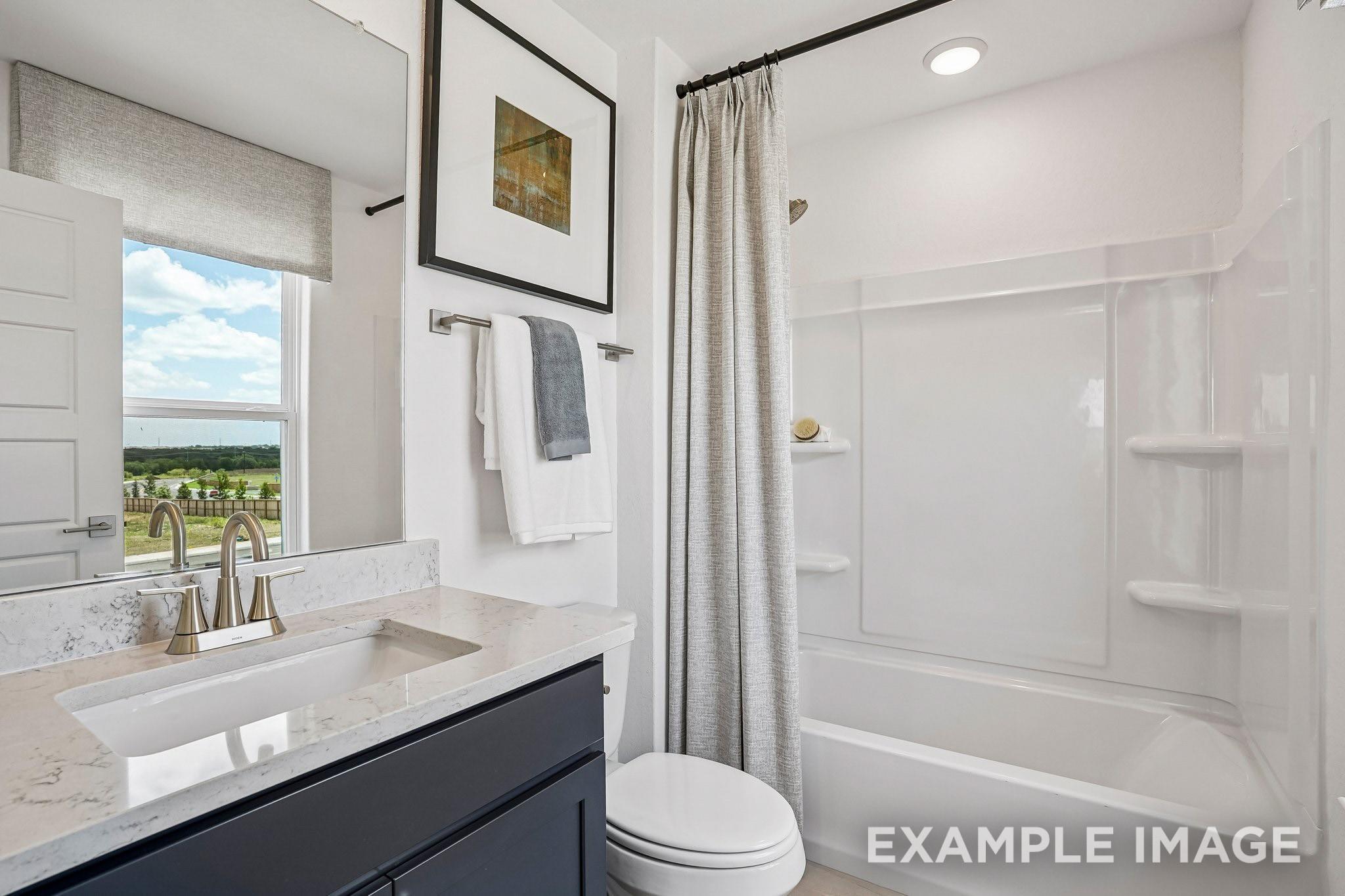 Modern bathroom with navy vanity, quartz countertop, and tub shower in Davidson Homes Ashport J plan, Sundance Cove, Crosby, TX
