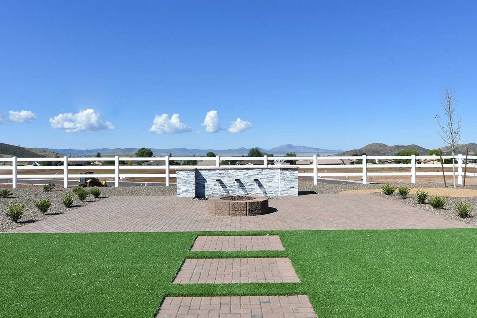 Tranquil community courtyard at Morningstar in Prescott Valley AZ with white stone fountain, brick fire pit, desert plants, and mountain backdrop